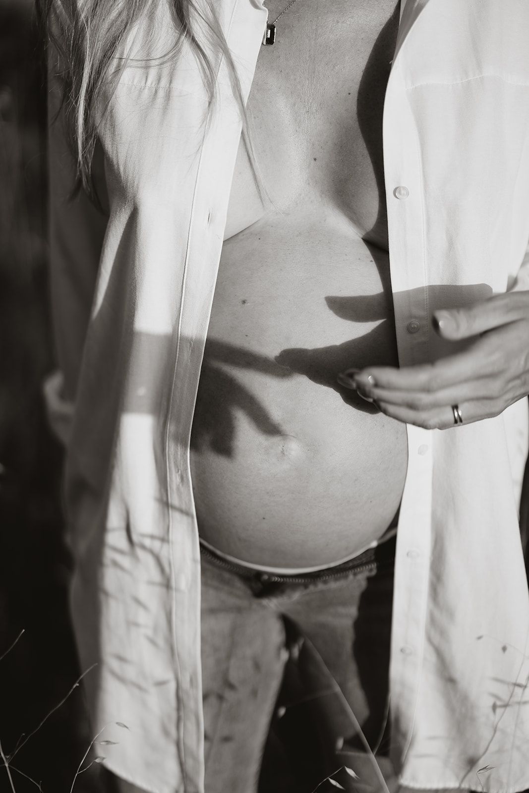 A black and white artistic photo showing a pregnant belly with shadows cast across it.