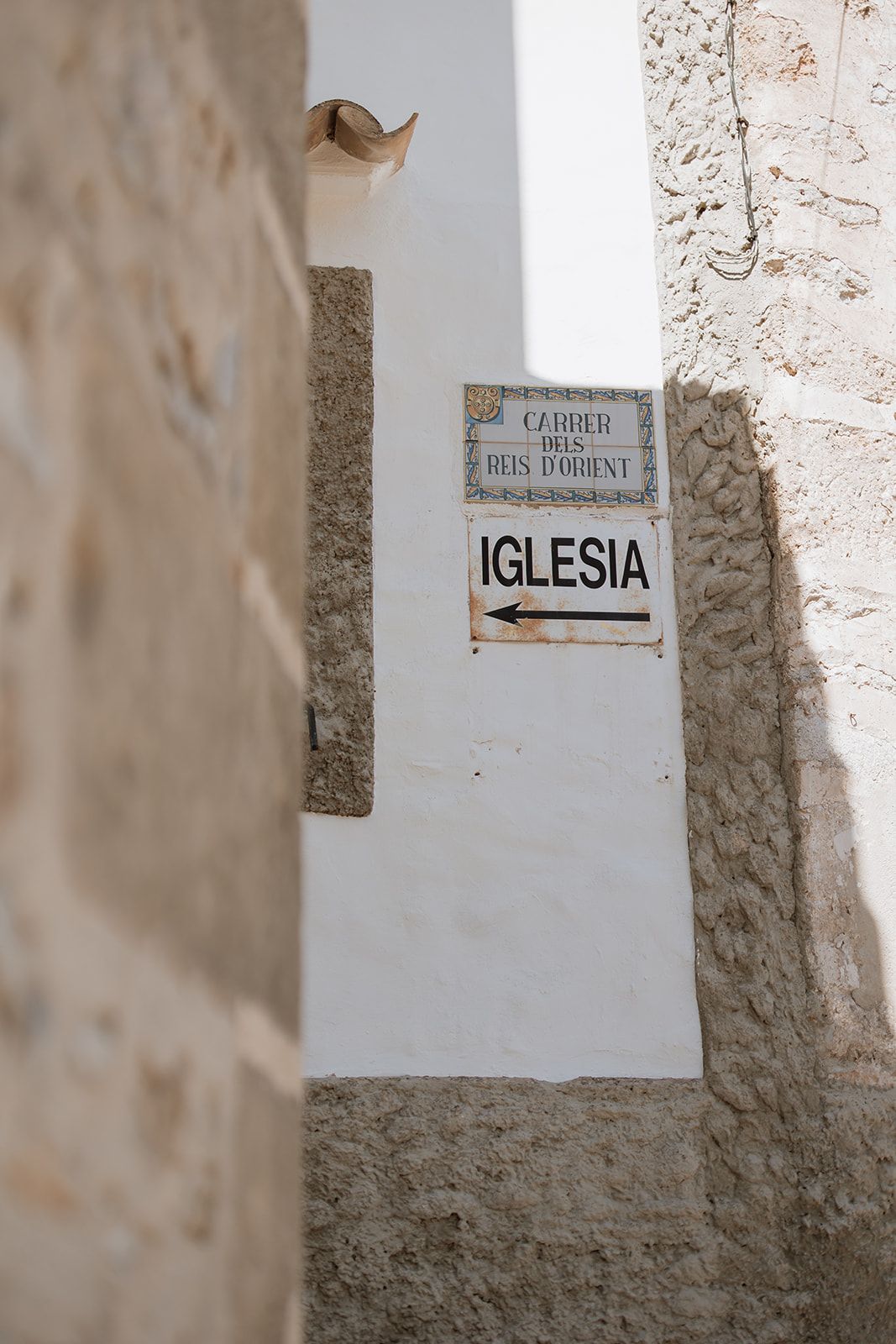 White stone wall with directional sign reading 'Iglesia' and arrow pointing left.