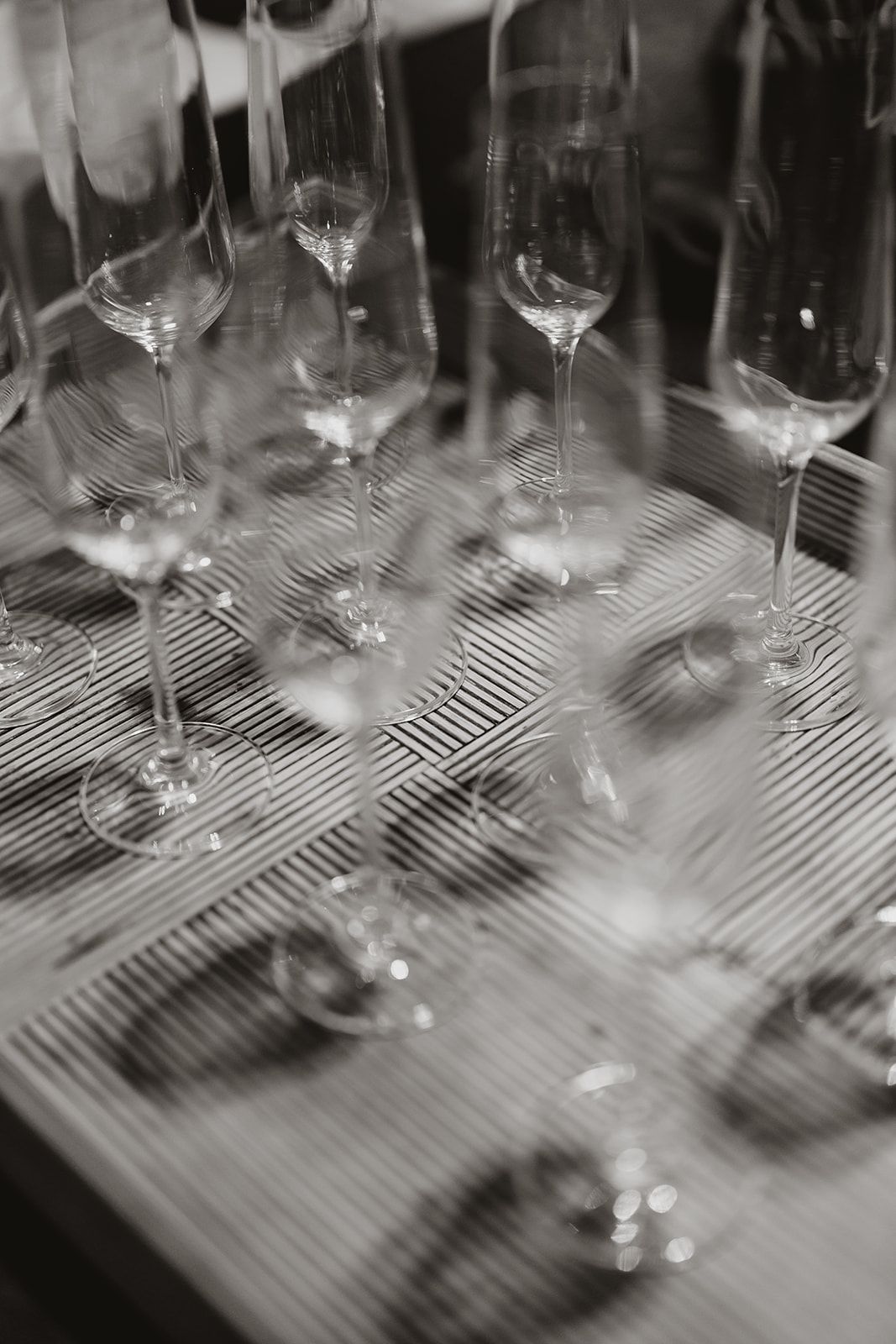 Collection of empty wine glasses arranged on a textured surface in black and white.