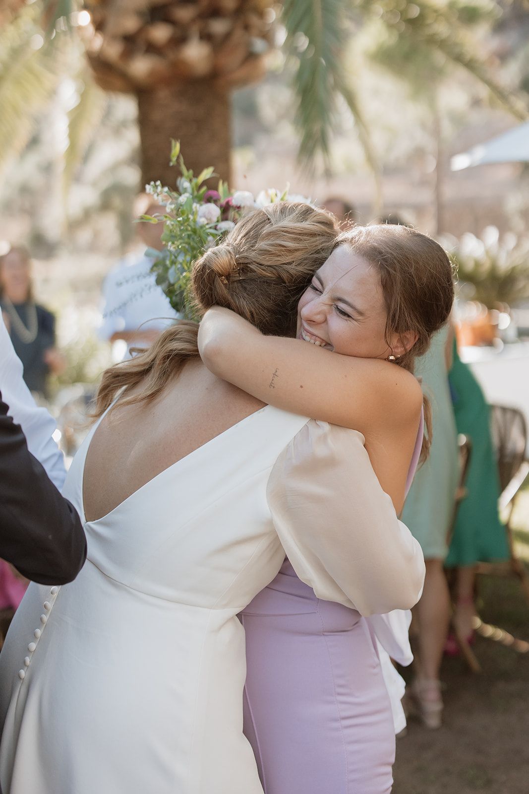 Wedding guests share warm embraces during outdoor celebration.
