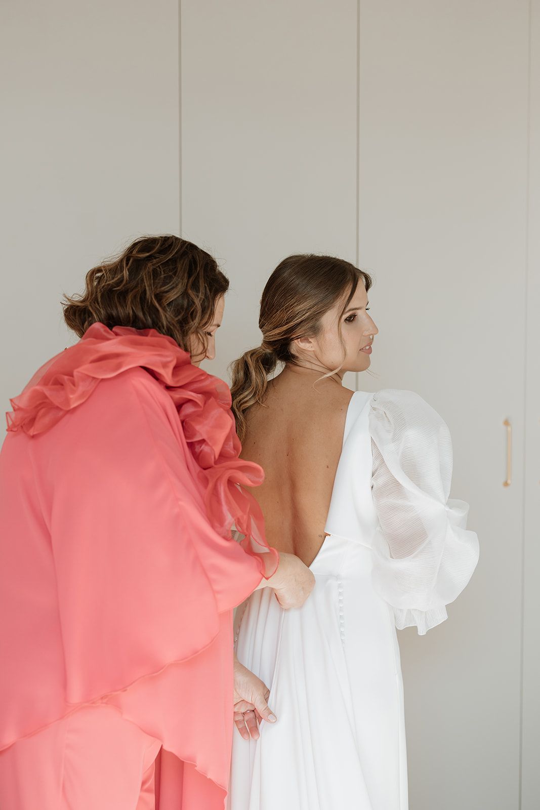 Wedding dress preparation scene with white gown and coral pink robe.