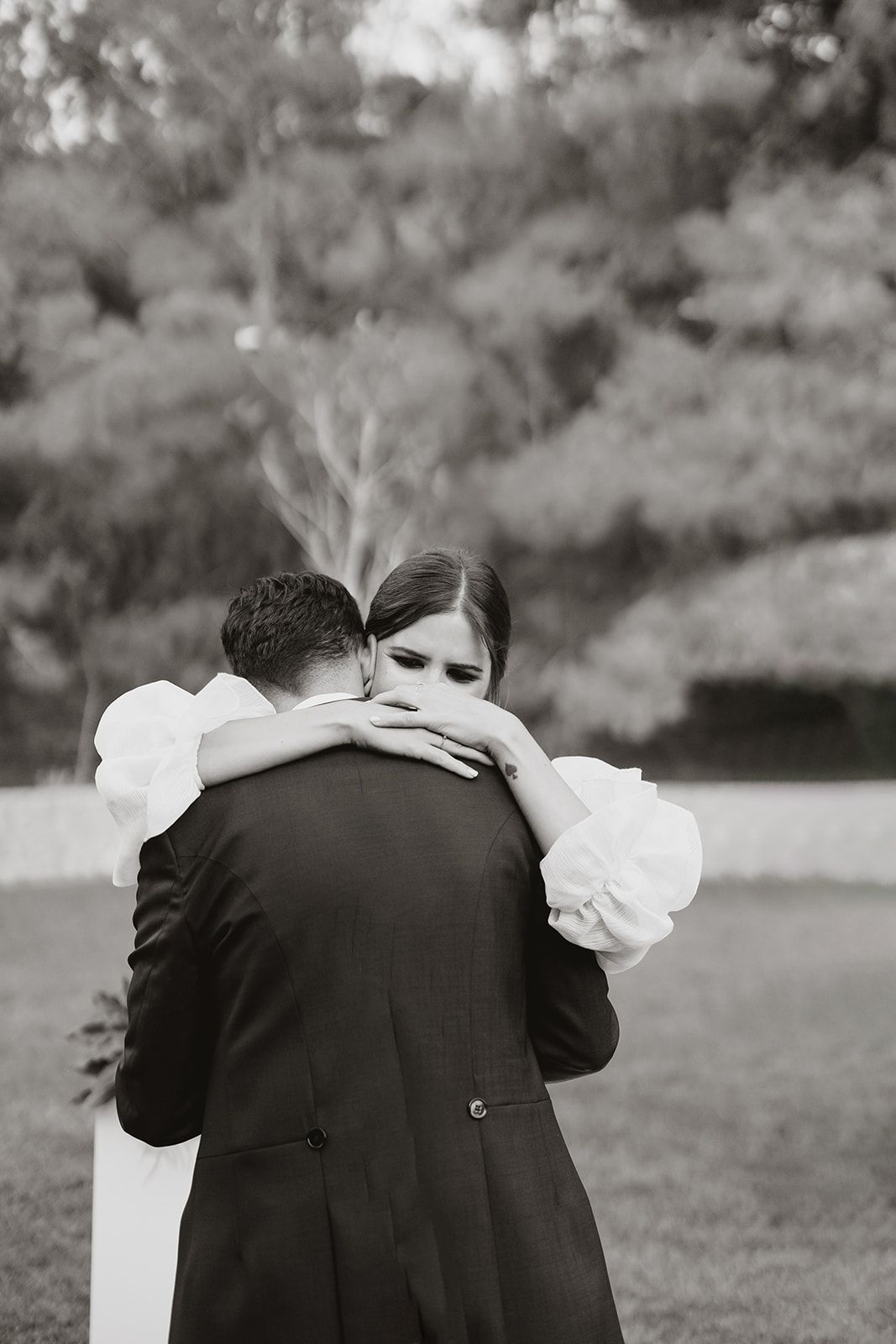 An emotional black and white portrait of a couple embracing during their wedding.