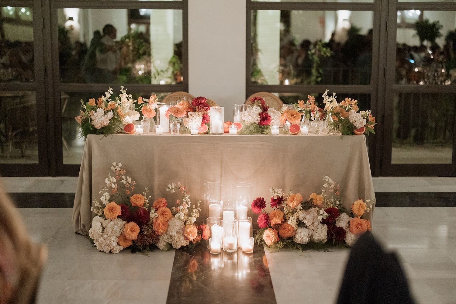 Elegantly decorated wedding head table with candlelight and floral arrangements.
