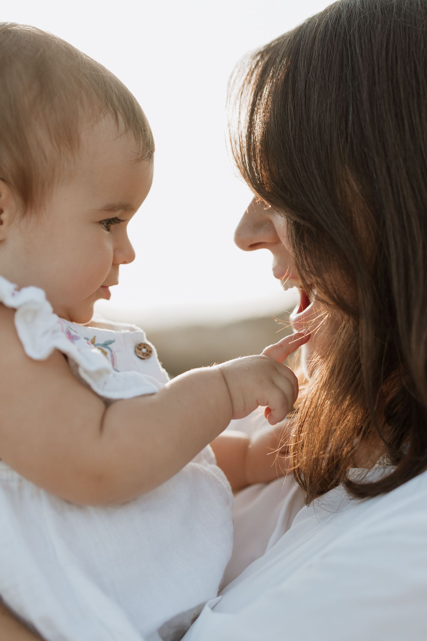 Intimate moment between caregiver and baby touching faces during outdoor session.