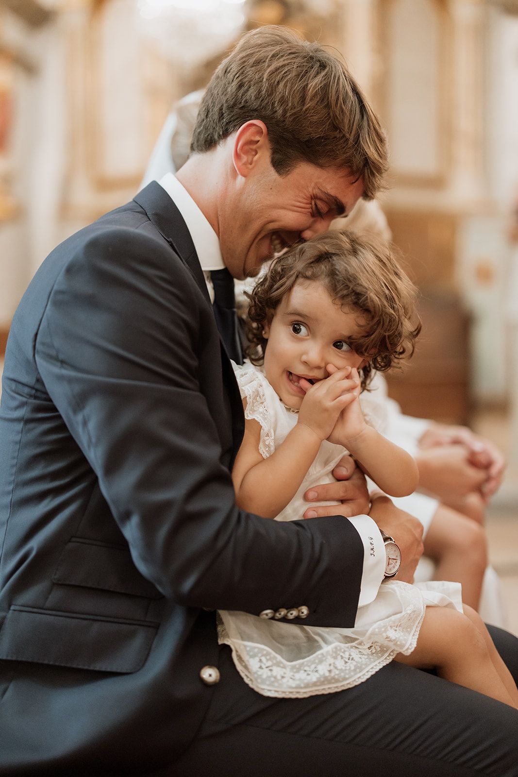 Heartwarming moment shared between groom and young flower girl during wedding celebration.