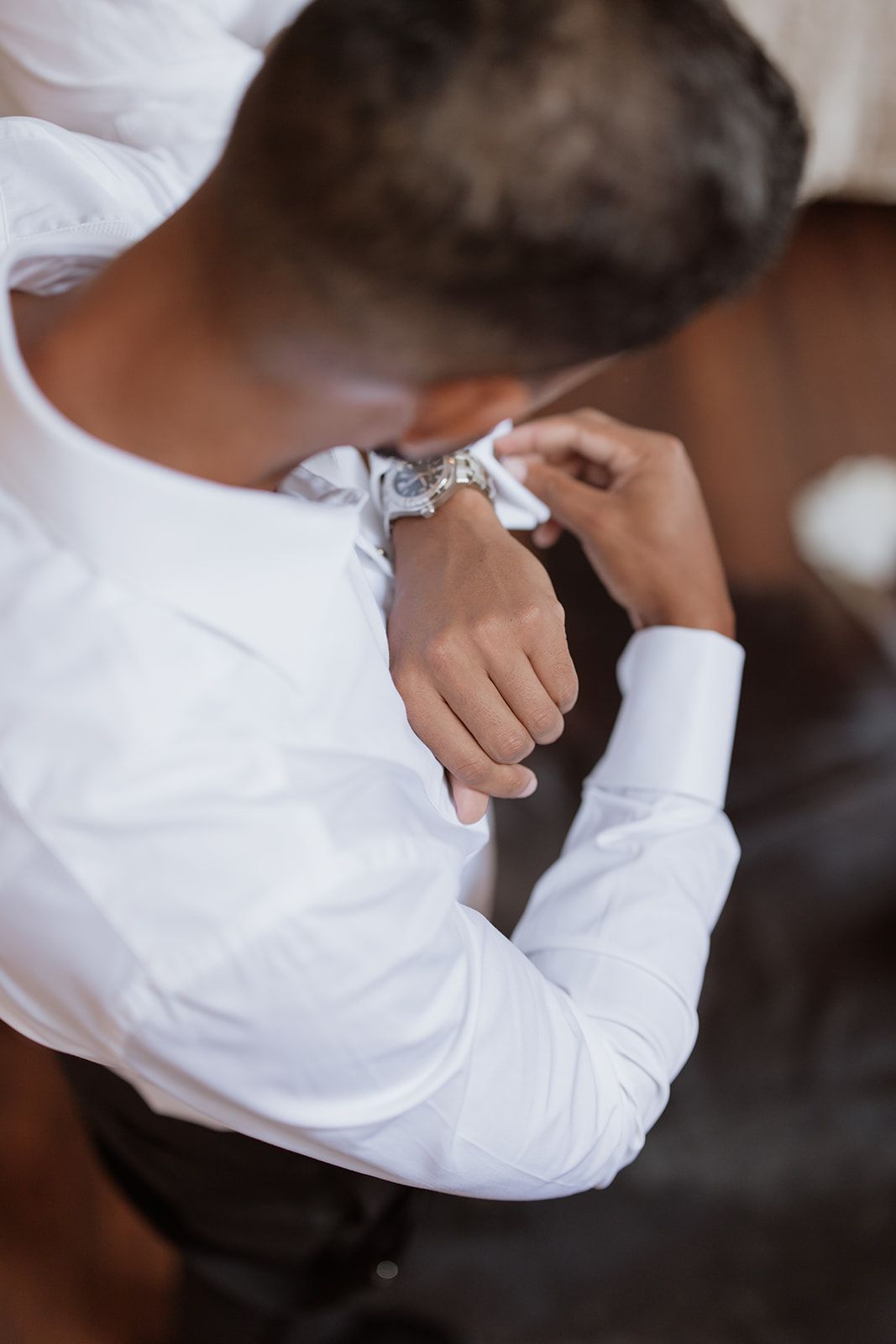 Close-up of hands adjusting a white dress shirt cuff and watch before a formal event.