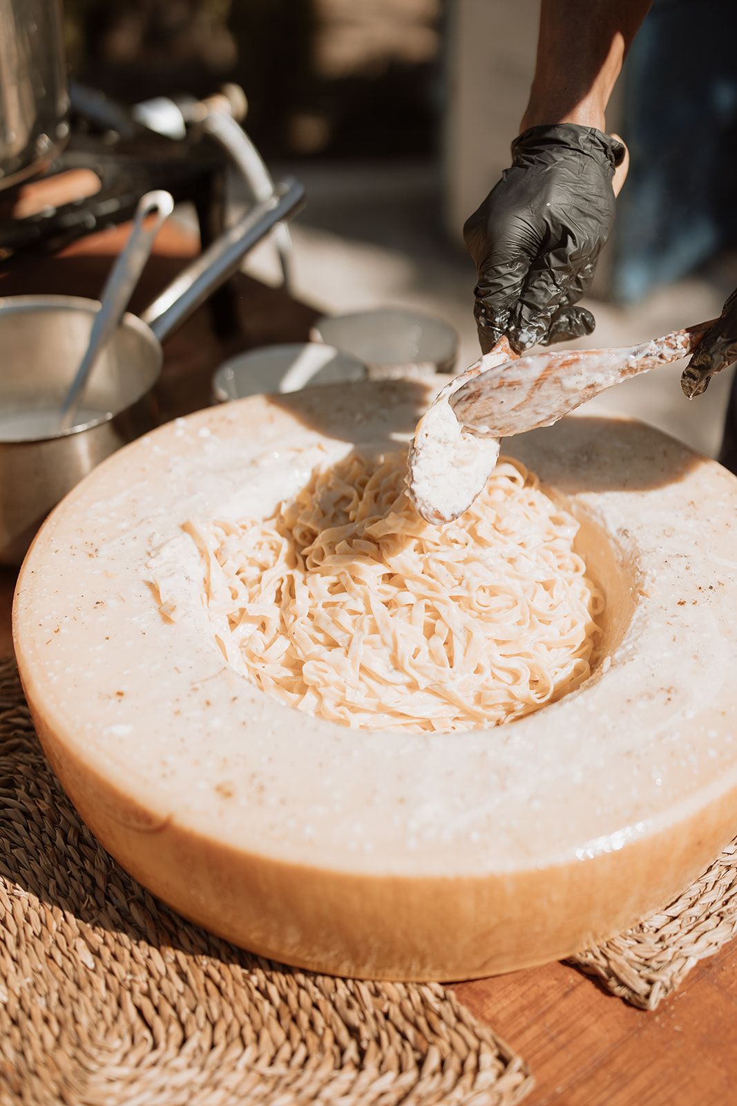 Chef in black gloves preparing cream filling in large mixing bowl at catering event.