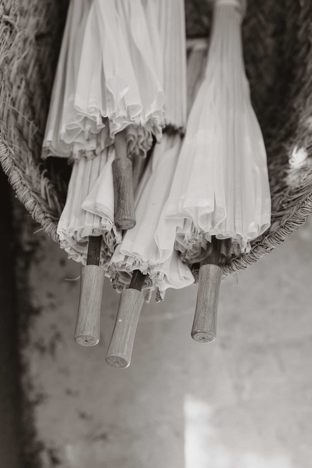 Vintage black and white photograph of white parasols hanging on wooden poles.