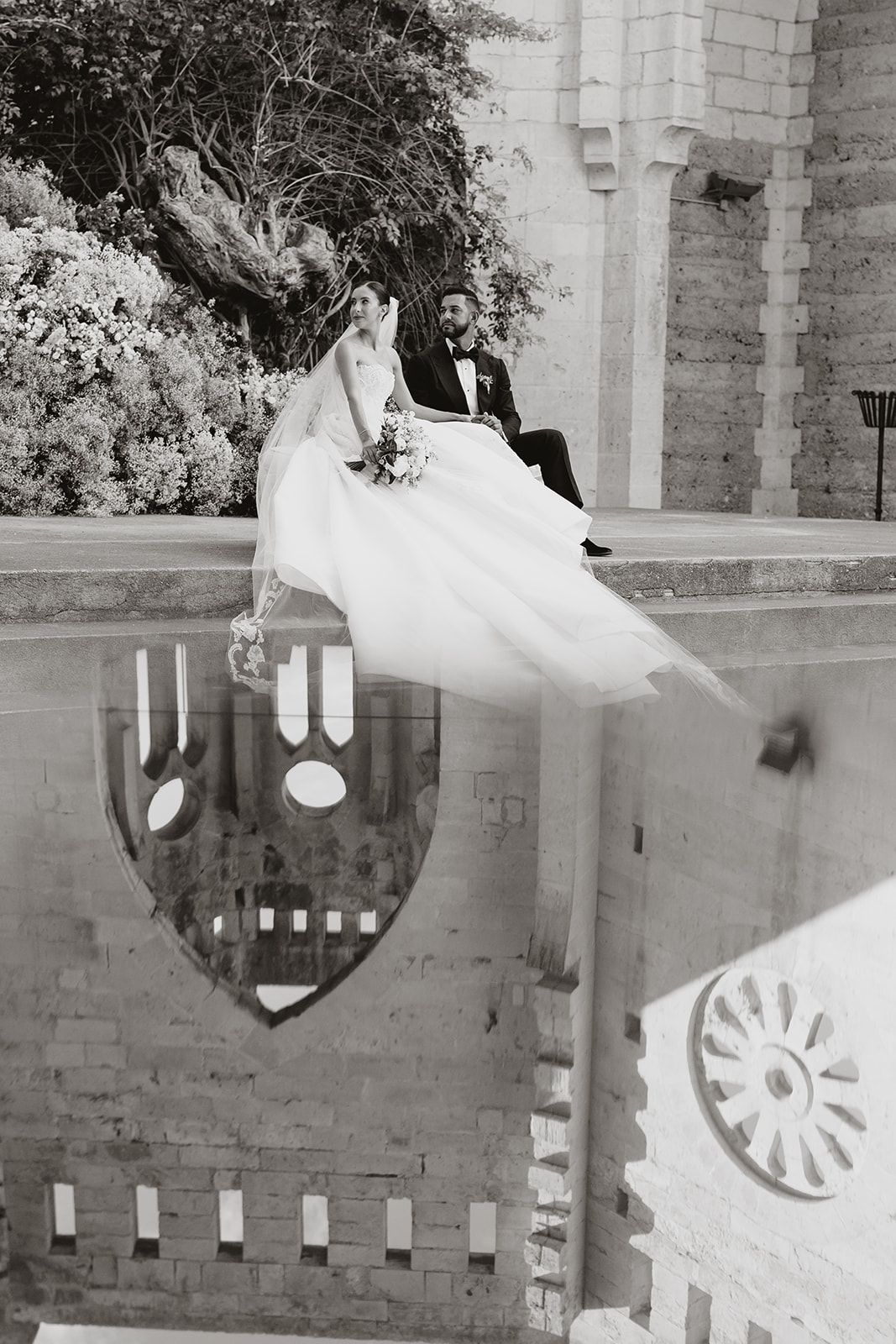 Artistically framed black and white wedding photo with reflection in cathedral architecture.