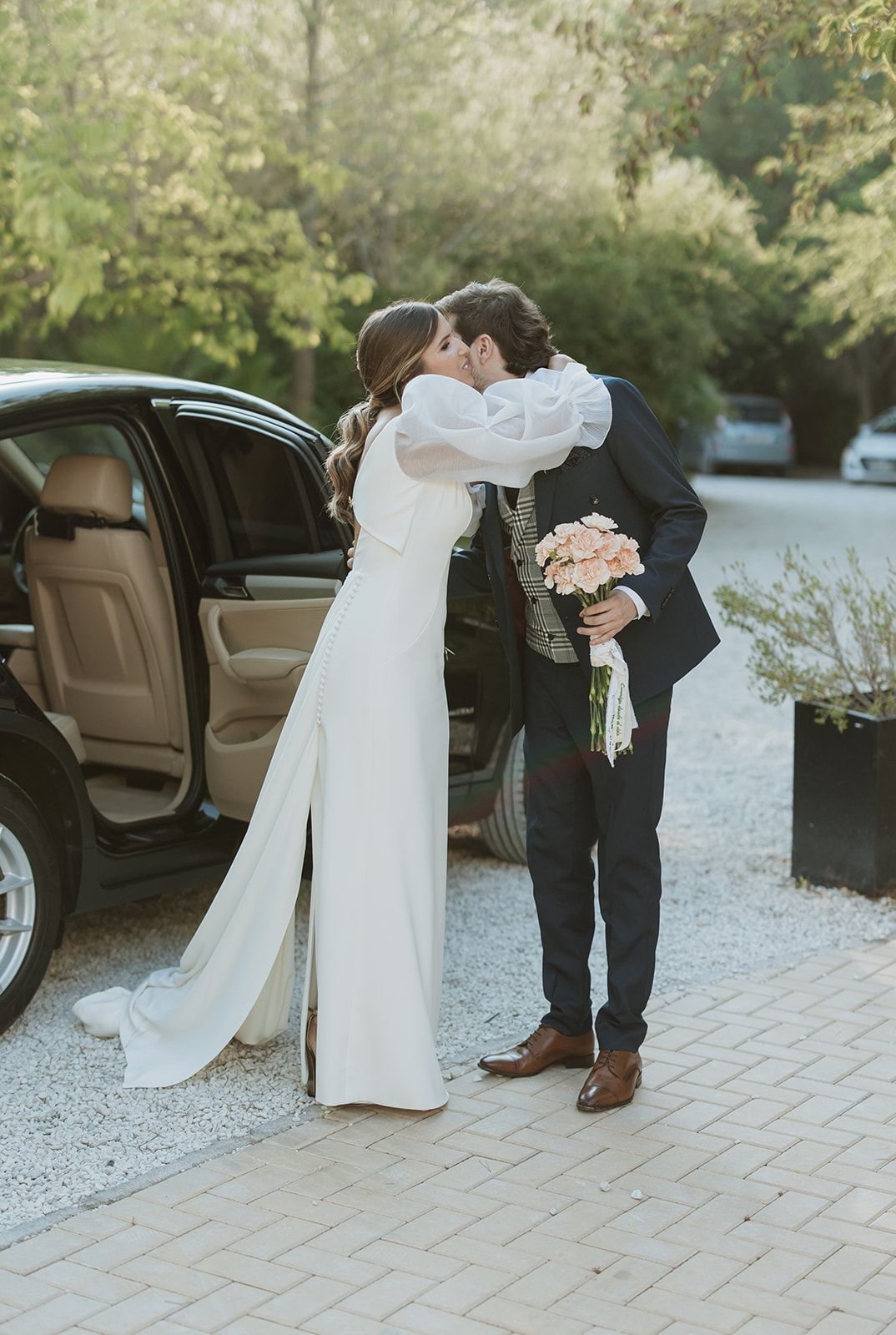 A romantic outdoor wedding moment captured by a luxury car with a floral bouquet.