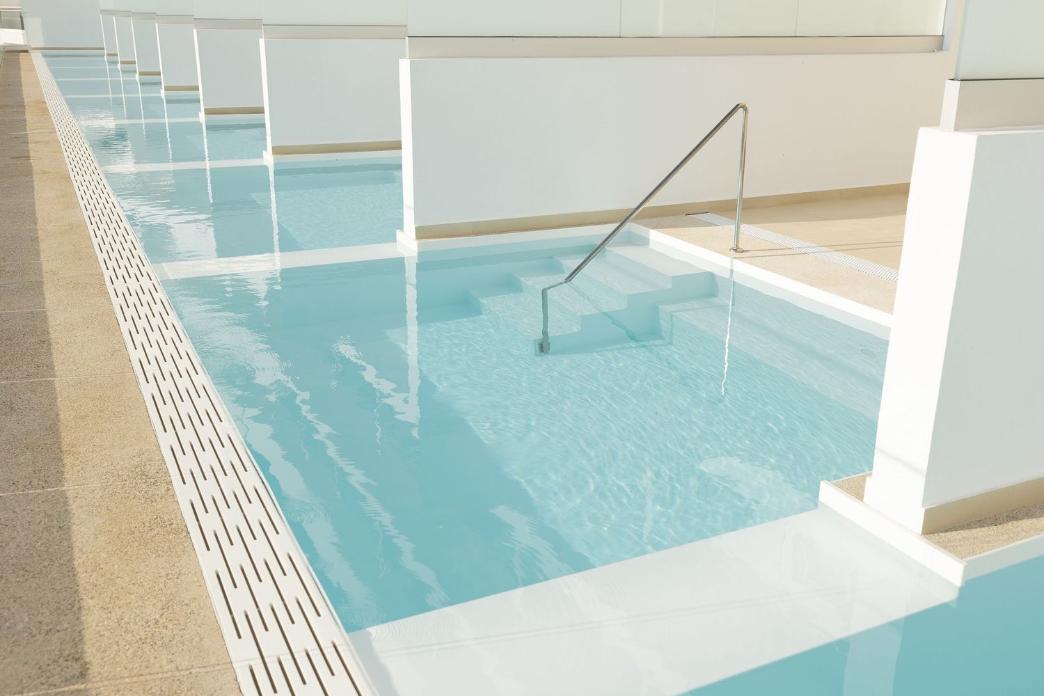 Modern pool design with safety handrail and textured border creating a serene aquatic environment.