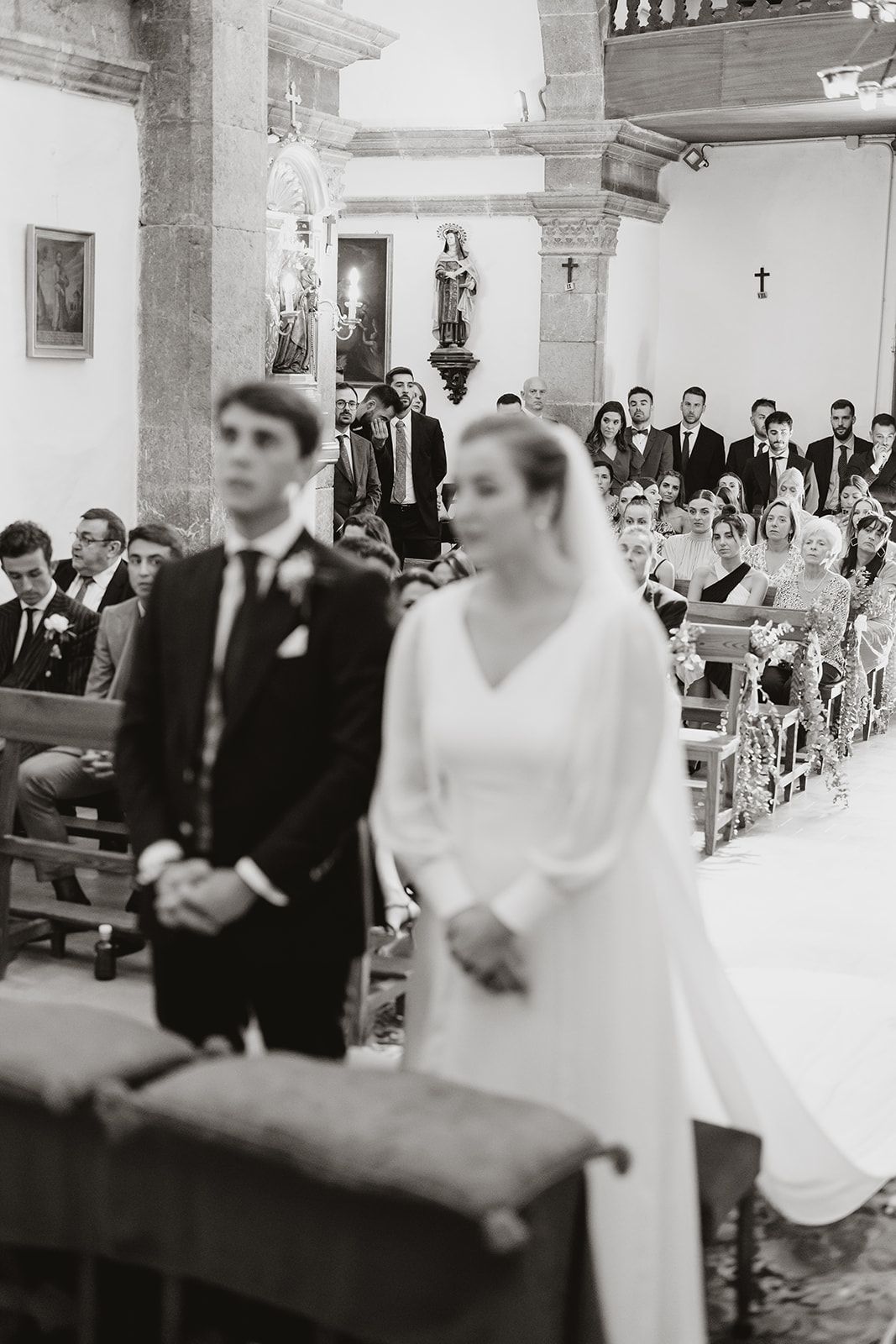 A traditional church wedding ceremony with guests seated in pews as a couple stands at the altar.