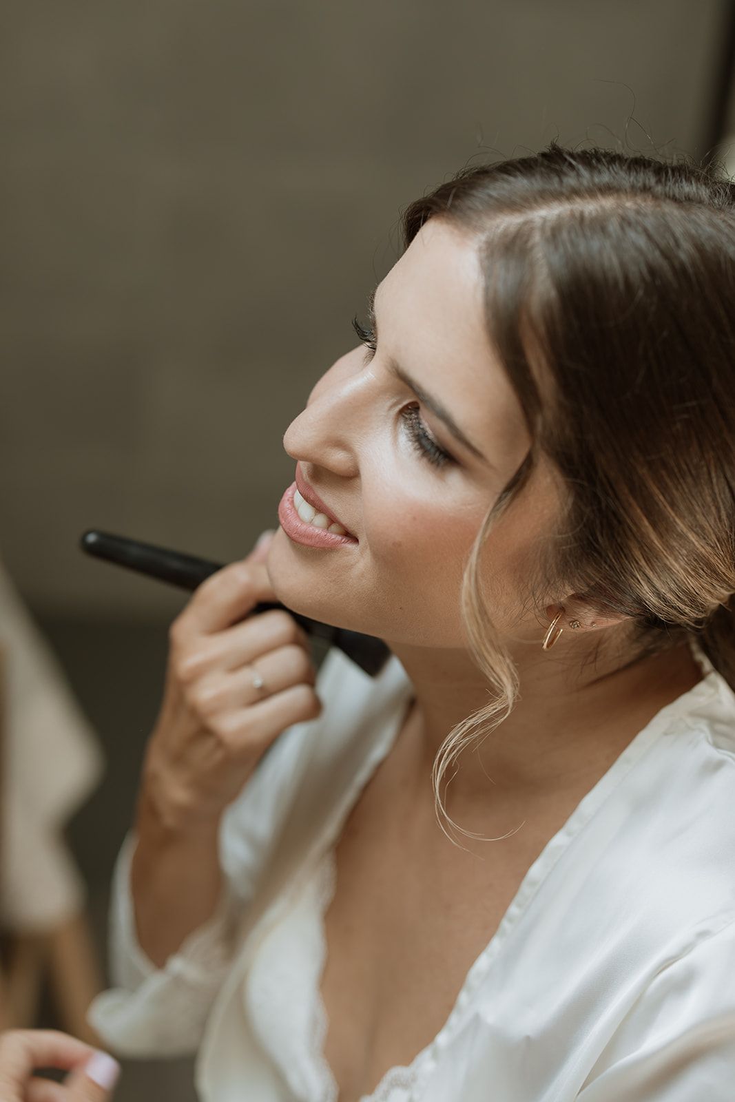 Close-up beauty shot of someone getting makeup applied while wearing a white robe.
