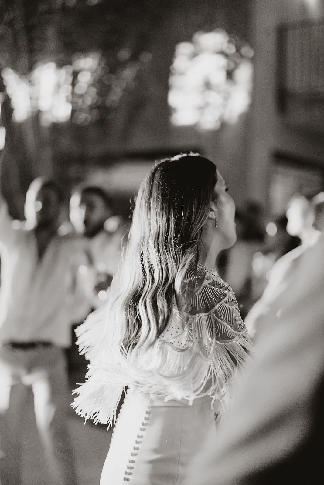 Black and white portrait of a bride in a detailed lace dress at her wedding reception.