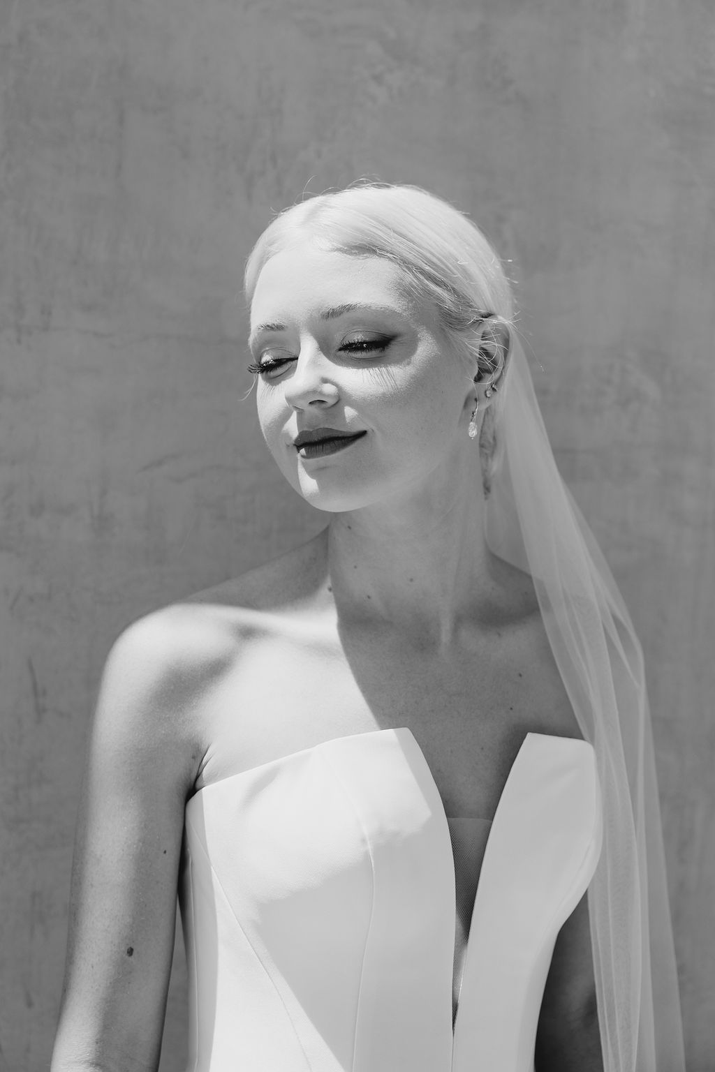 Elegant bridal portrait in black and white showing a modern wedding dress with plunging neckline.