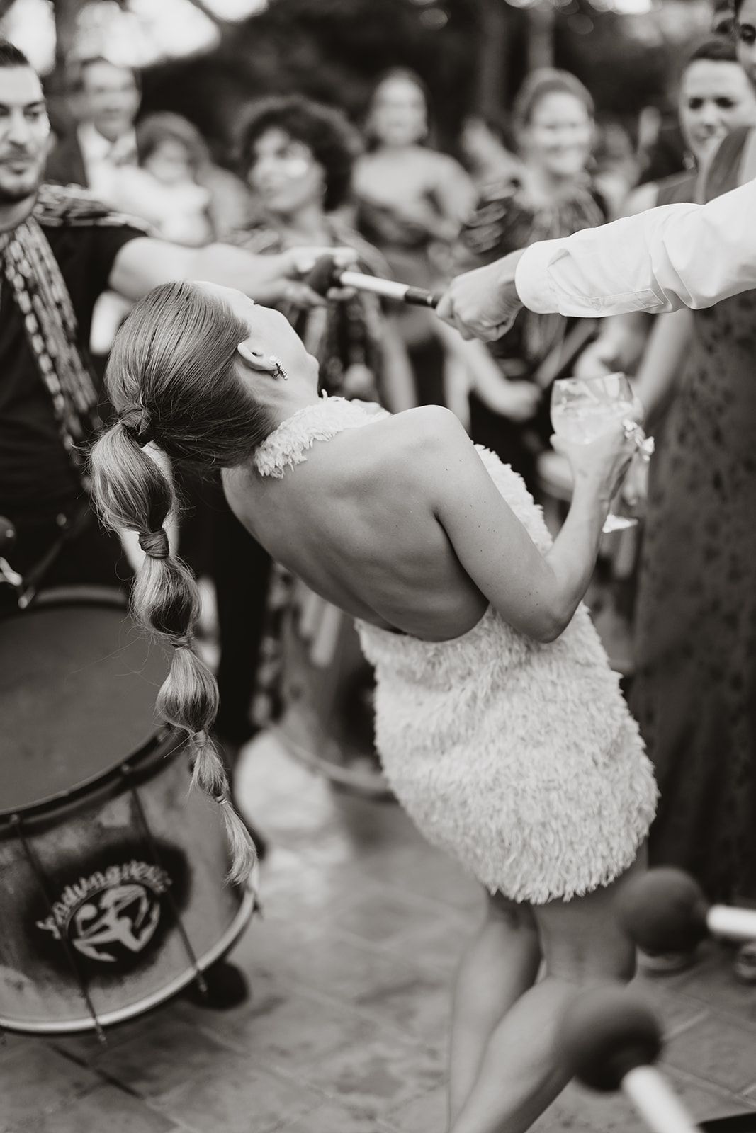 A bride in a short dress dips backward during a lively dance at her wedding reception.