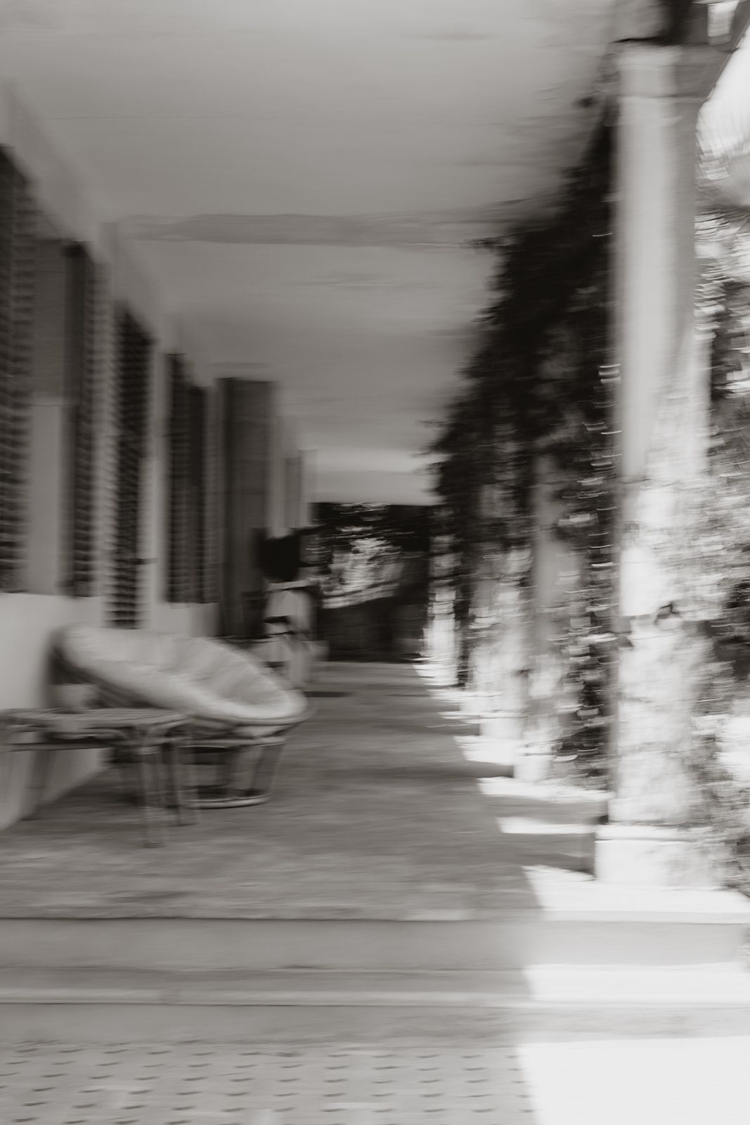 Blurred black and white architectural photograph of a covered walkway with columns.