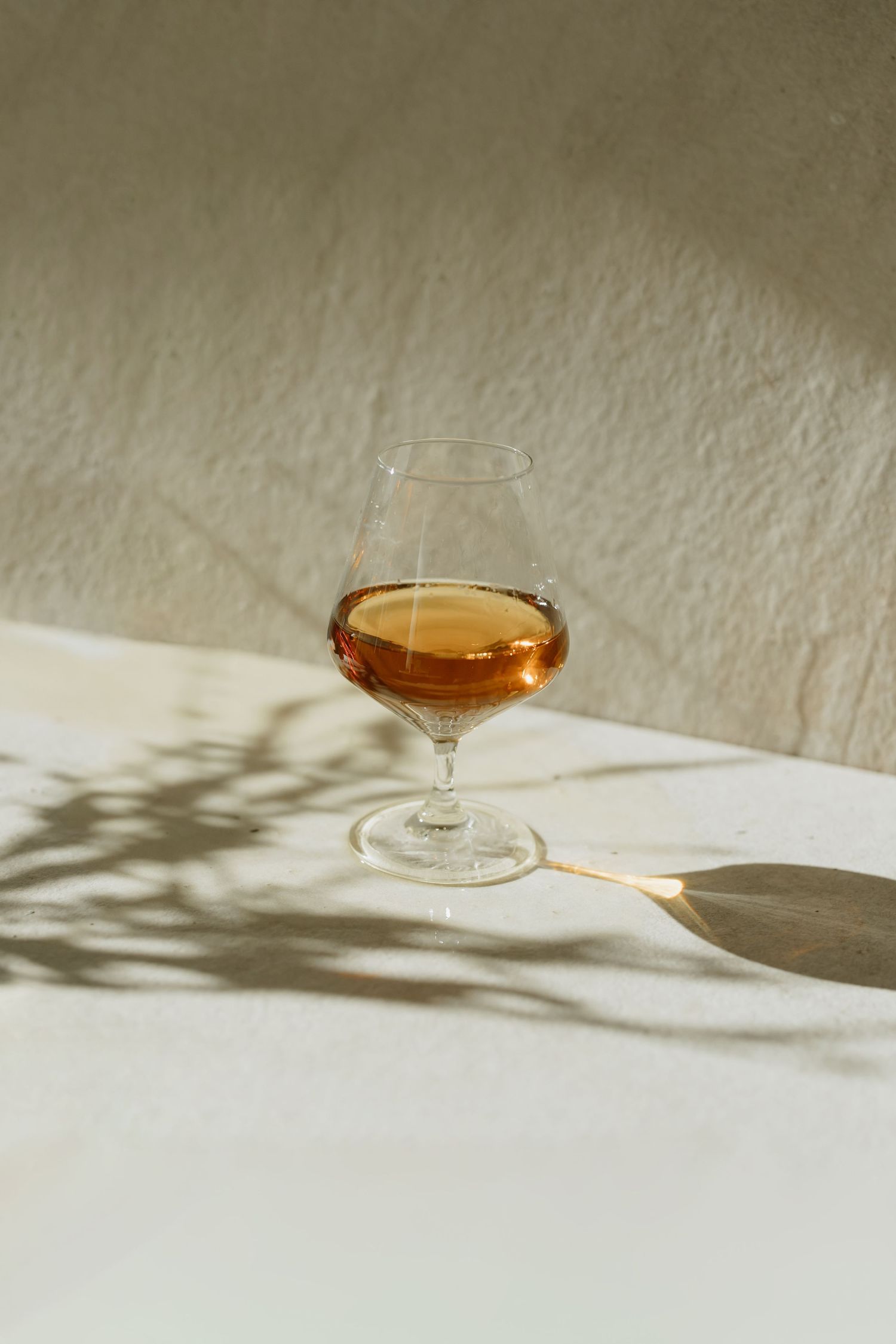 Cognac or brandy in stemmed glass with dramatic shadow play.