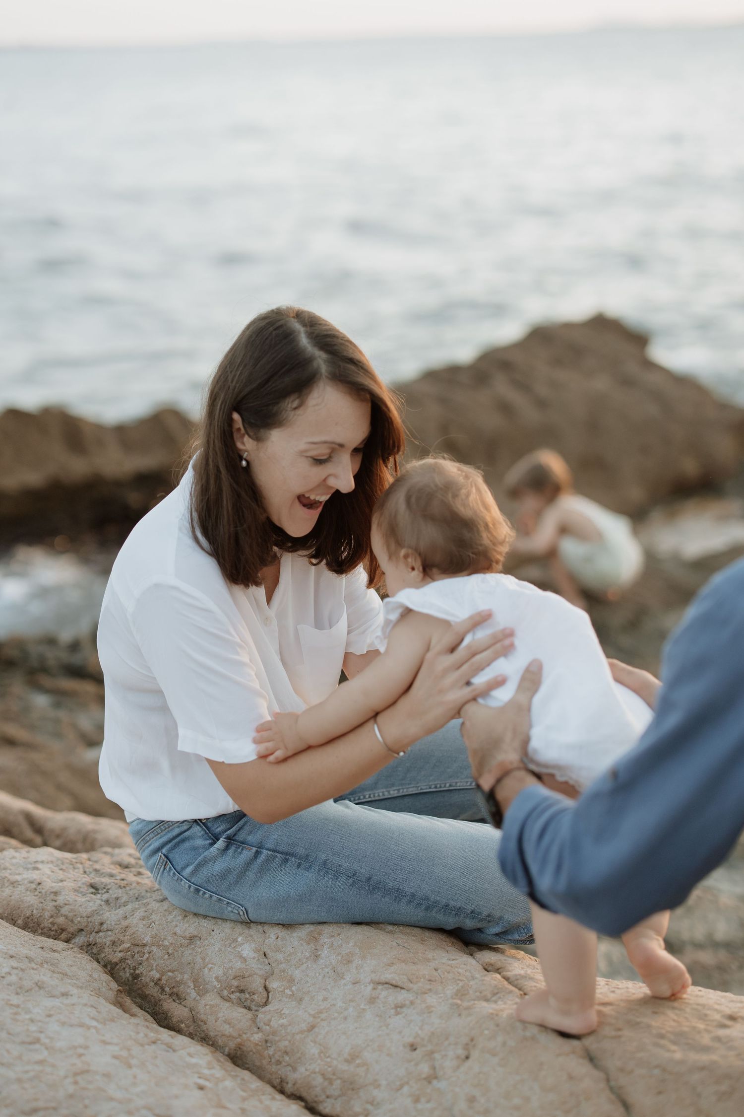 Mother and child share tender moments on coastal rocks during sunset photo session.