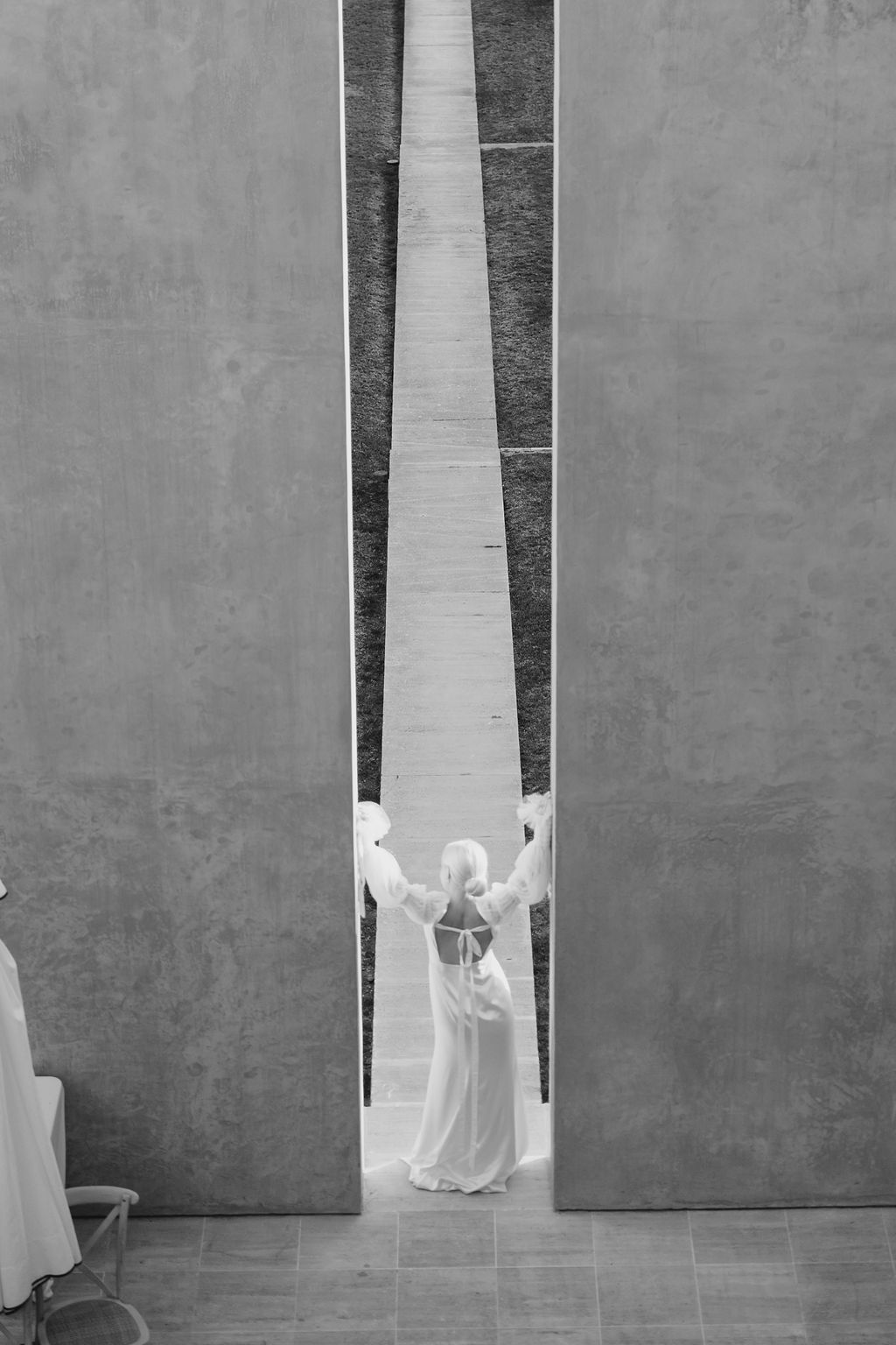 Dramatic black and white photograph of bridal gown centered in geometric architectural space.