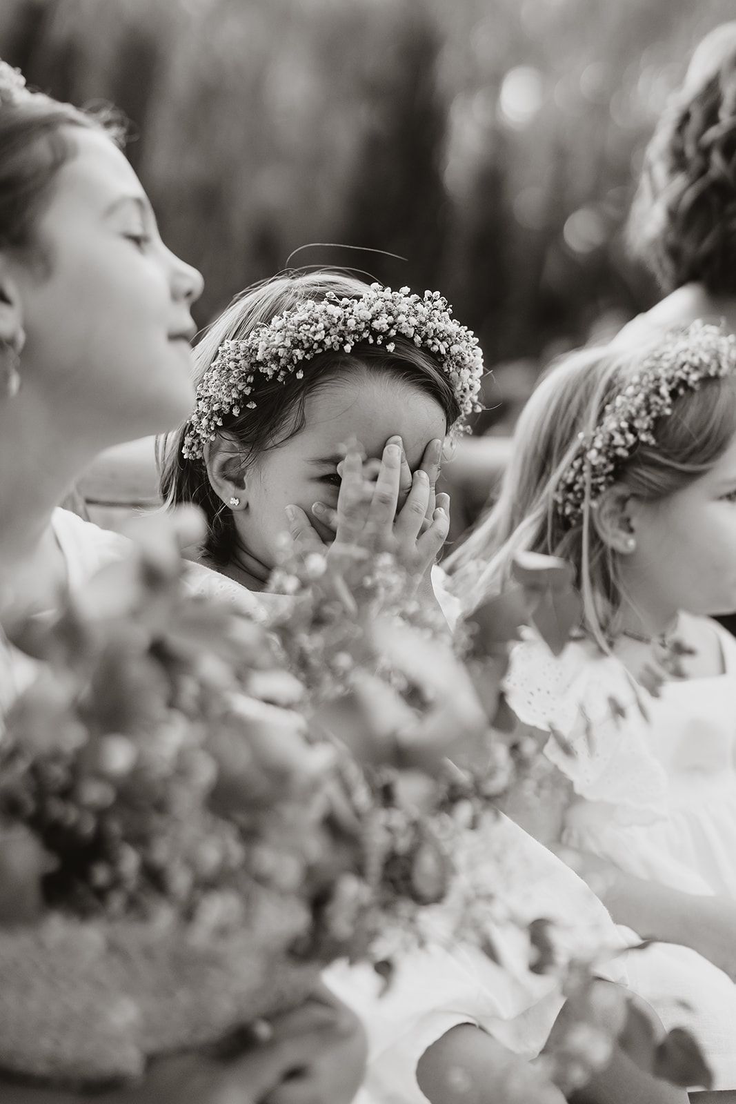 Black and white photograph of flower girls wearing delicate baby's breath crowns at a wedding.