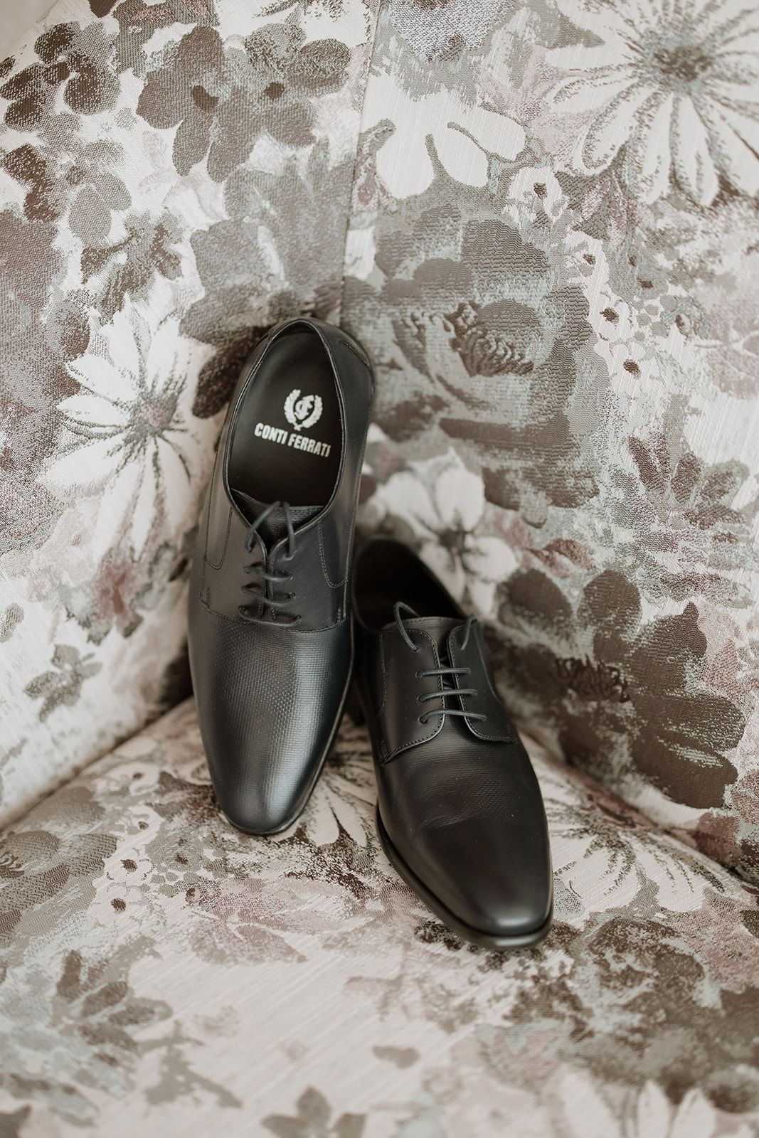 Elegant black leather dress shoes on a floral patterned background.
