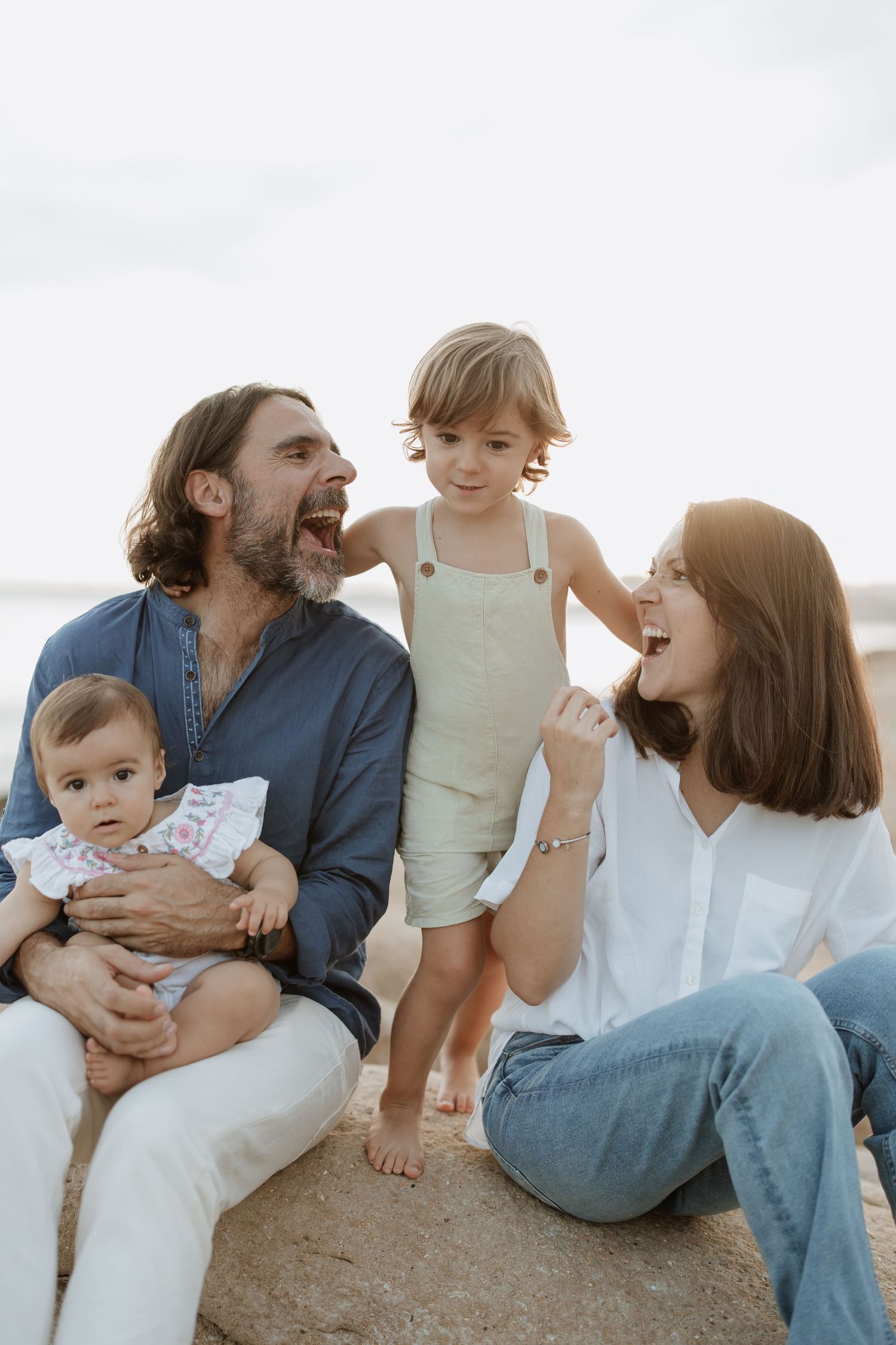 Joyful family moment captured on rocky beach as they laugh together.