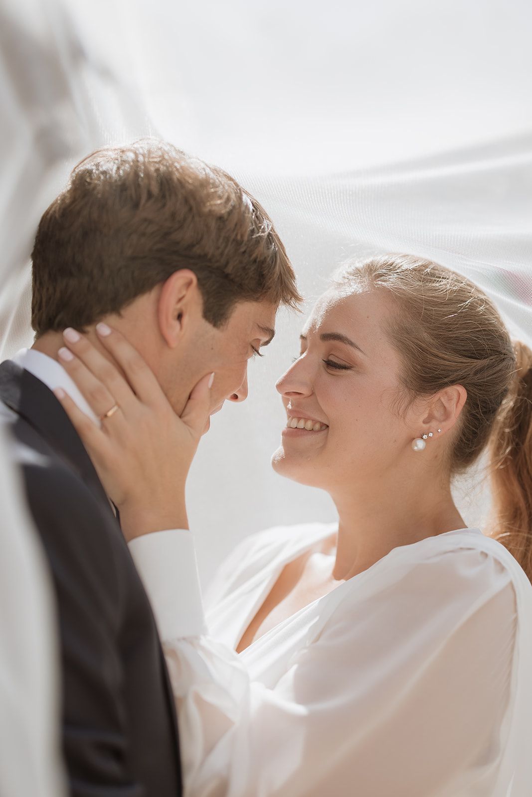 Romantic close-up of wedding couple embracing while sharing joyful smiles.