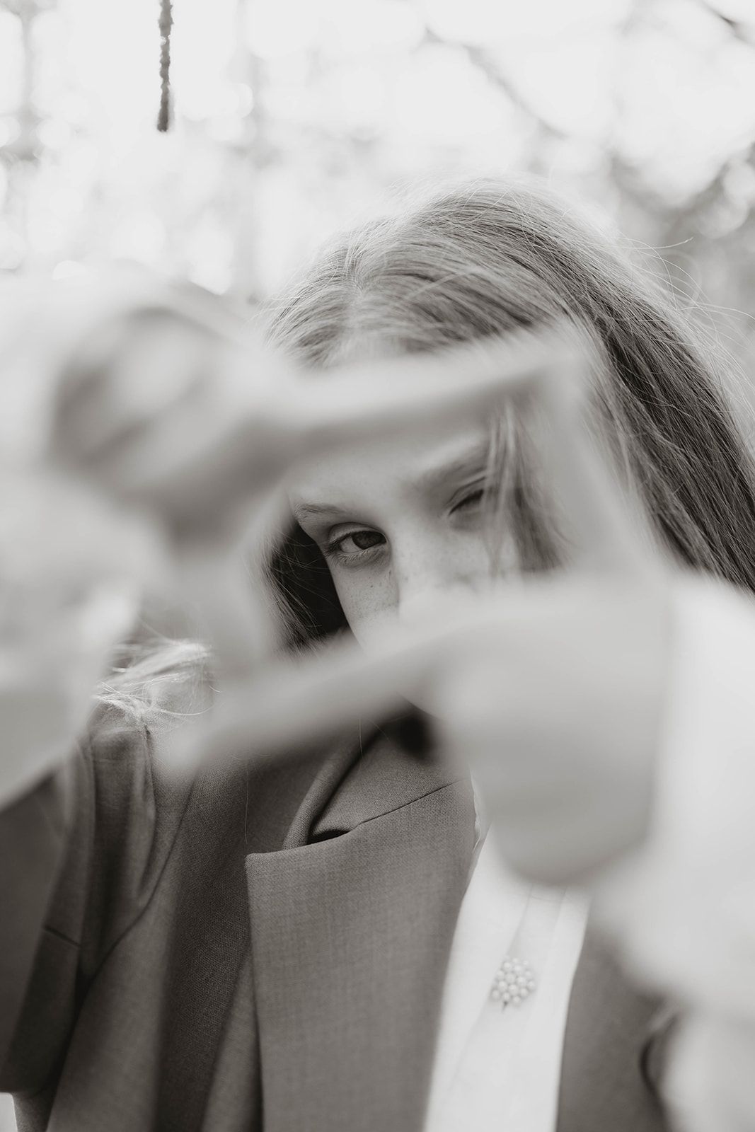 Artistic black and white portrait shot through blurred foreground elements creating depth.
