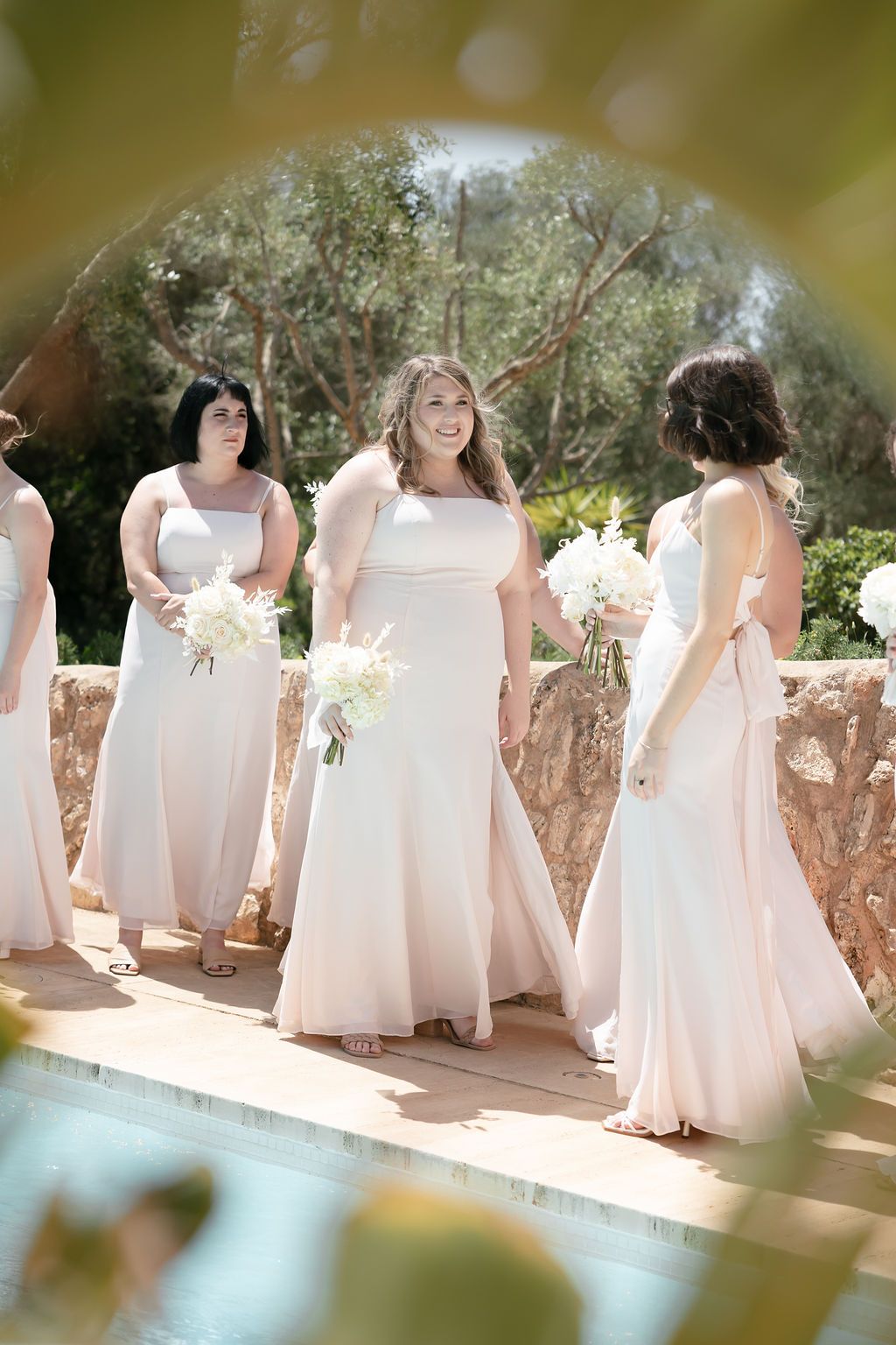 Bridesmaids in flowing blush pink dresses standing together outdoors.