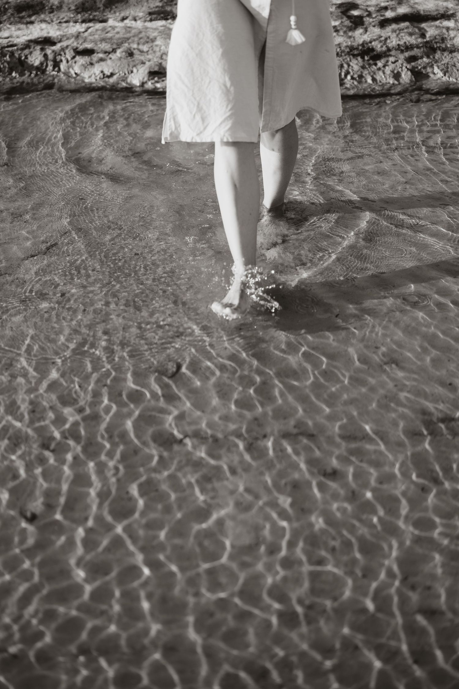 Black and white image of rippling shallow water over sand at the beach.