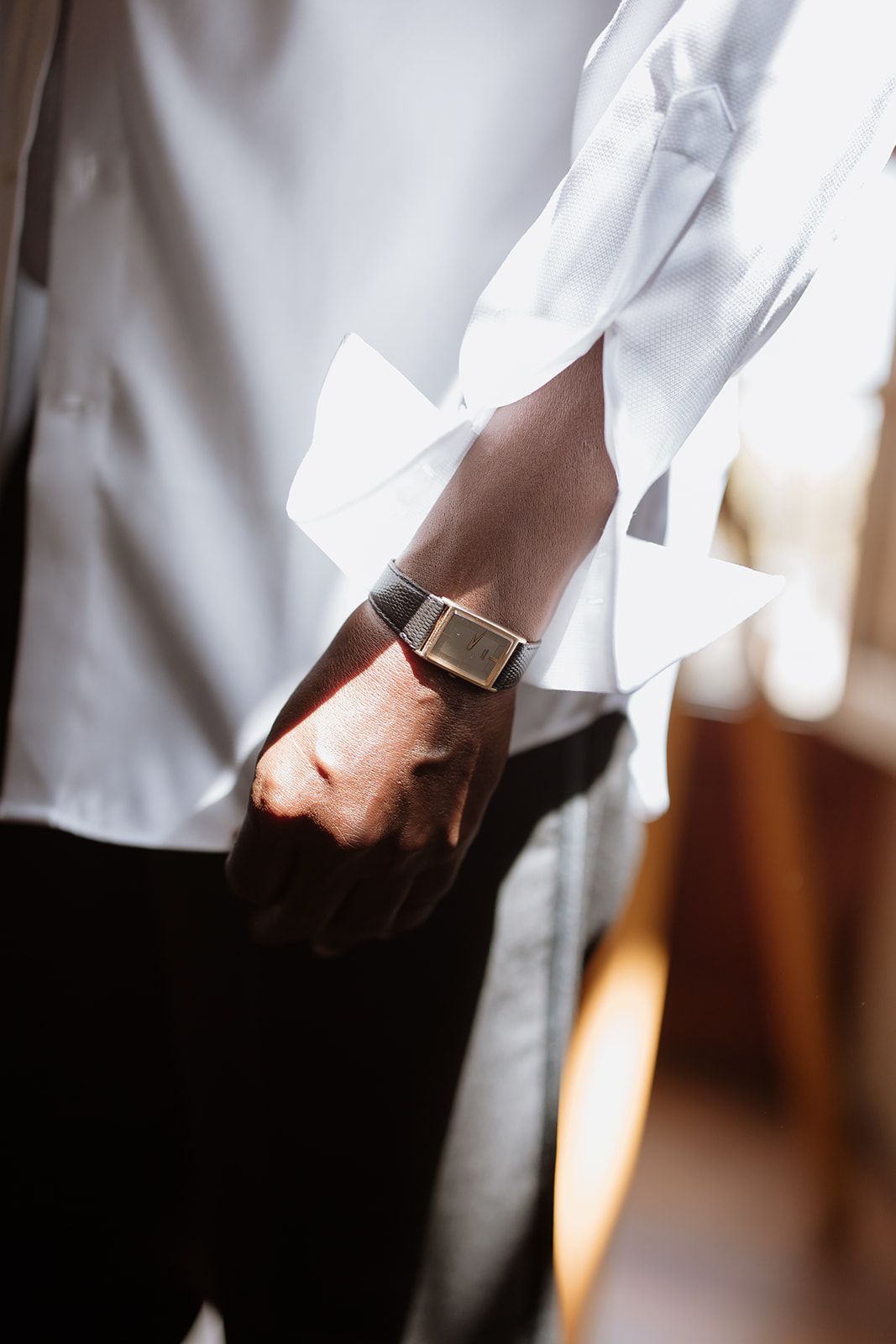 Close-up detail of a wristwatch with white dress shirt sleeve.