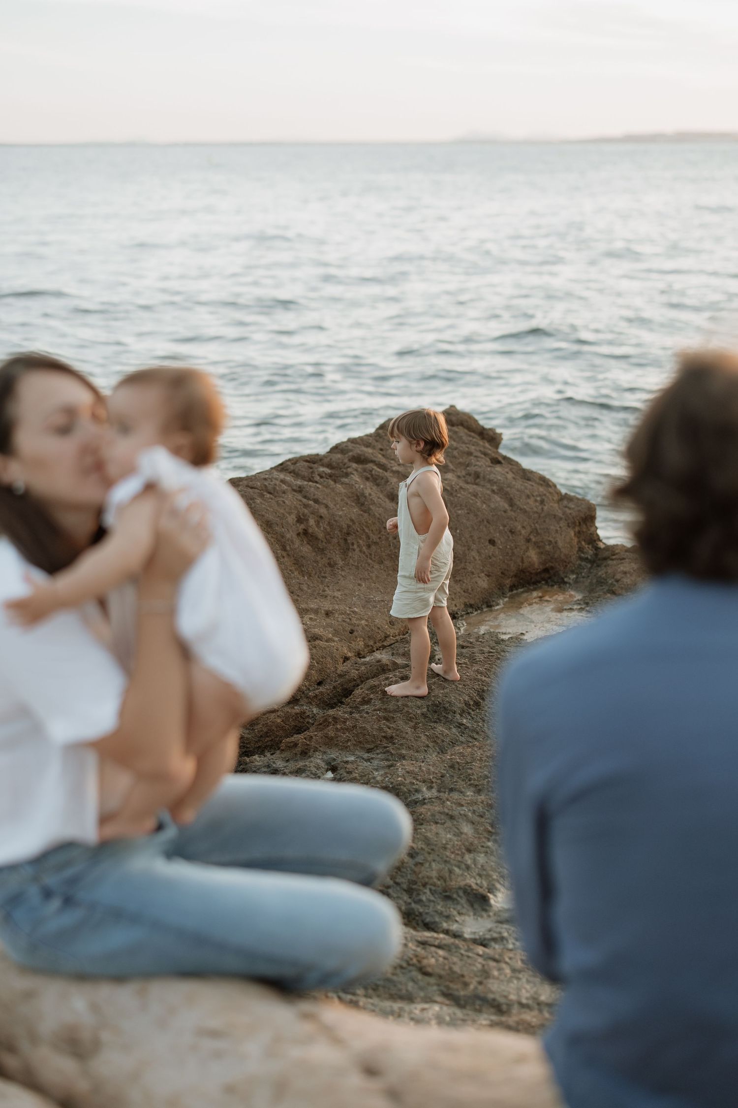 Family enjoying sunset beach adventure on rocky coast.
