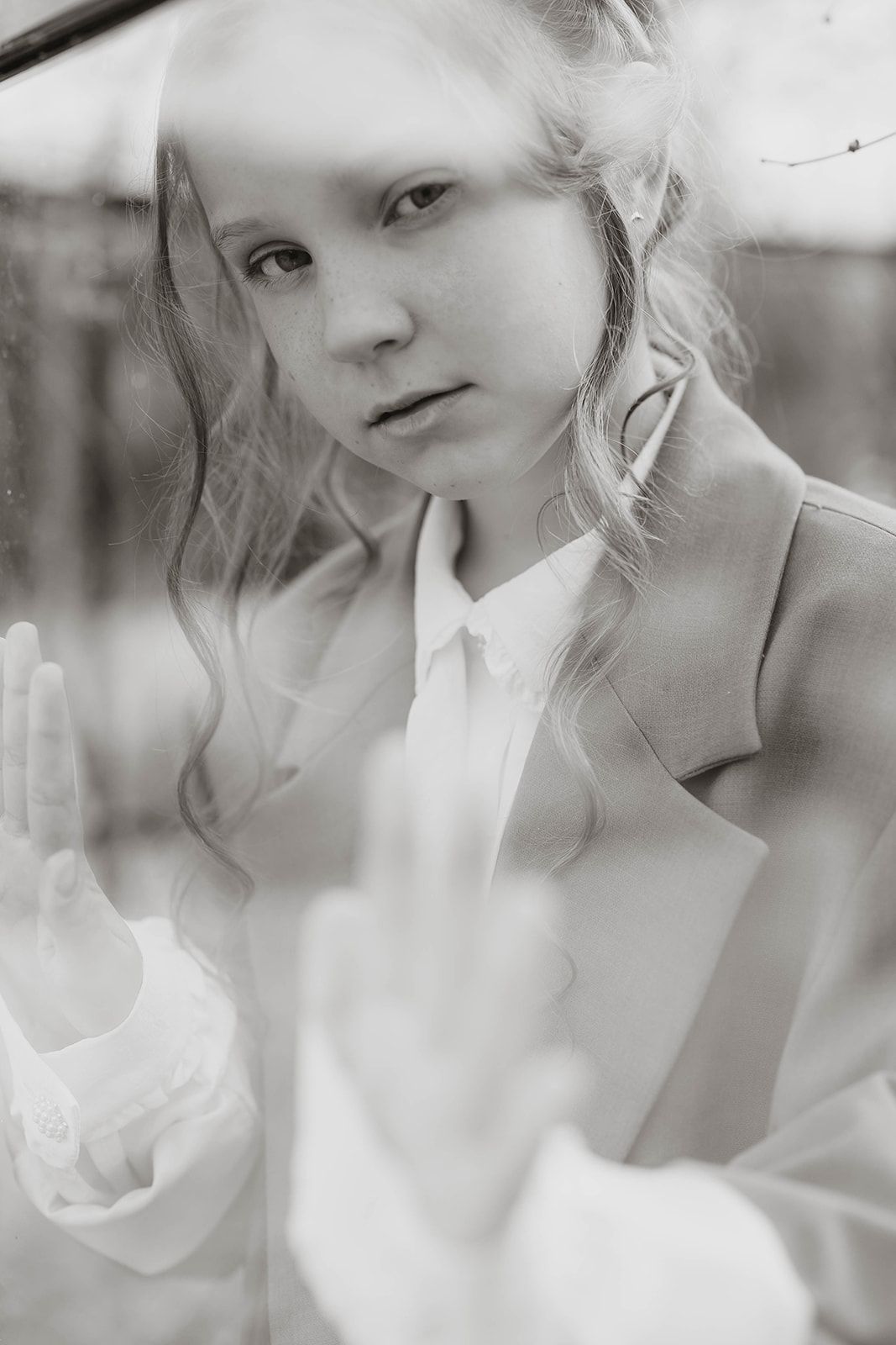 Black and white portrait with pressed hands against glass creating an ethereal effect.