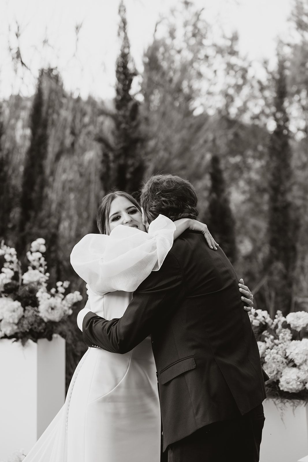 Black and white photo capturing an emotional embrace during a wedding ceremony.