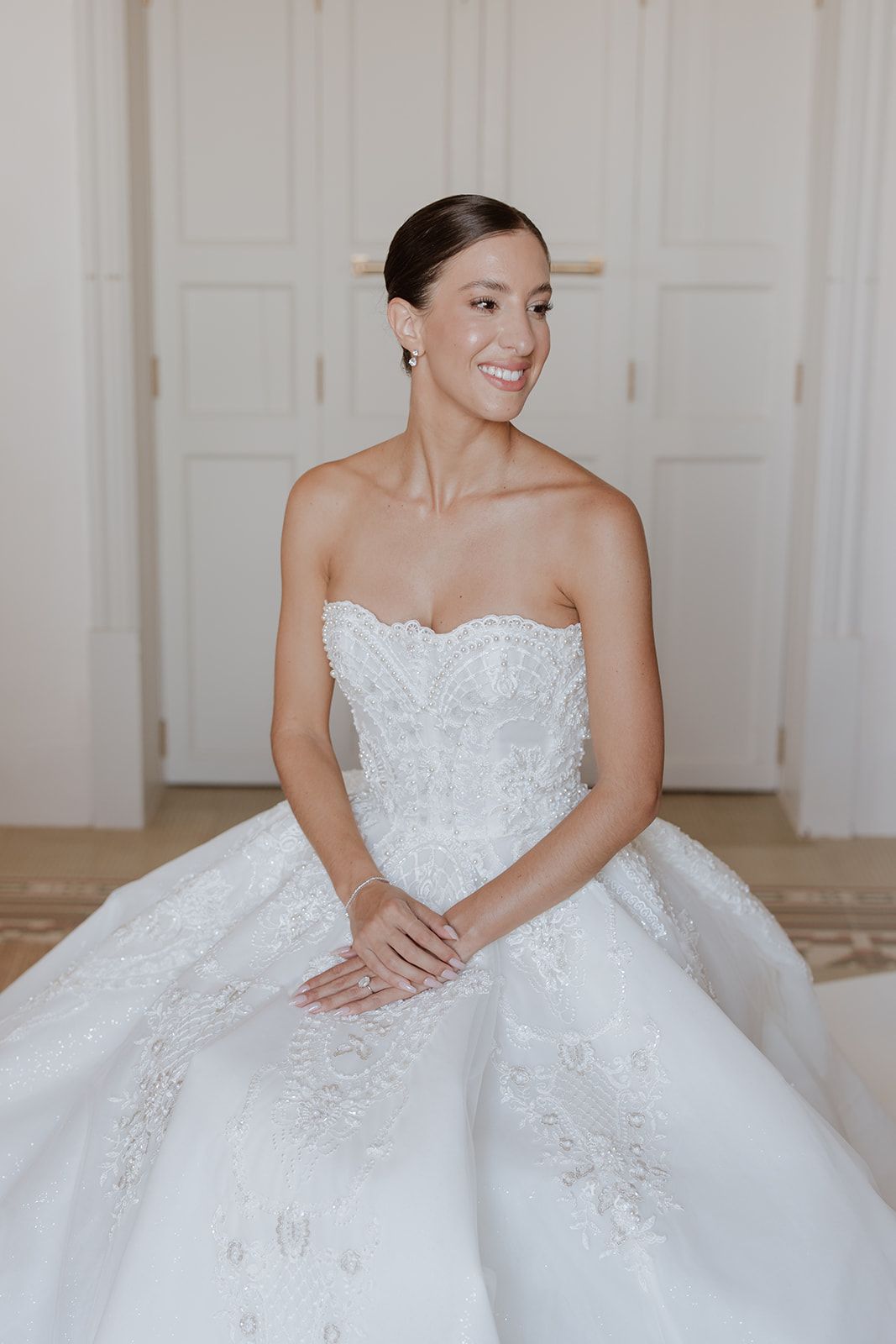 Elegant strapless wedding gown with voluminous skirt photographed in a bright white room.
