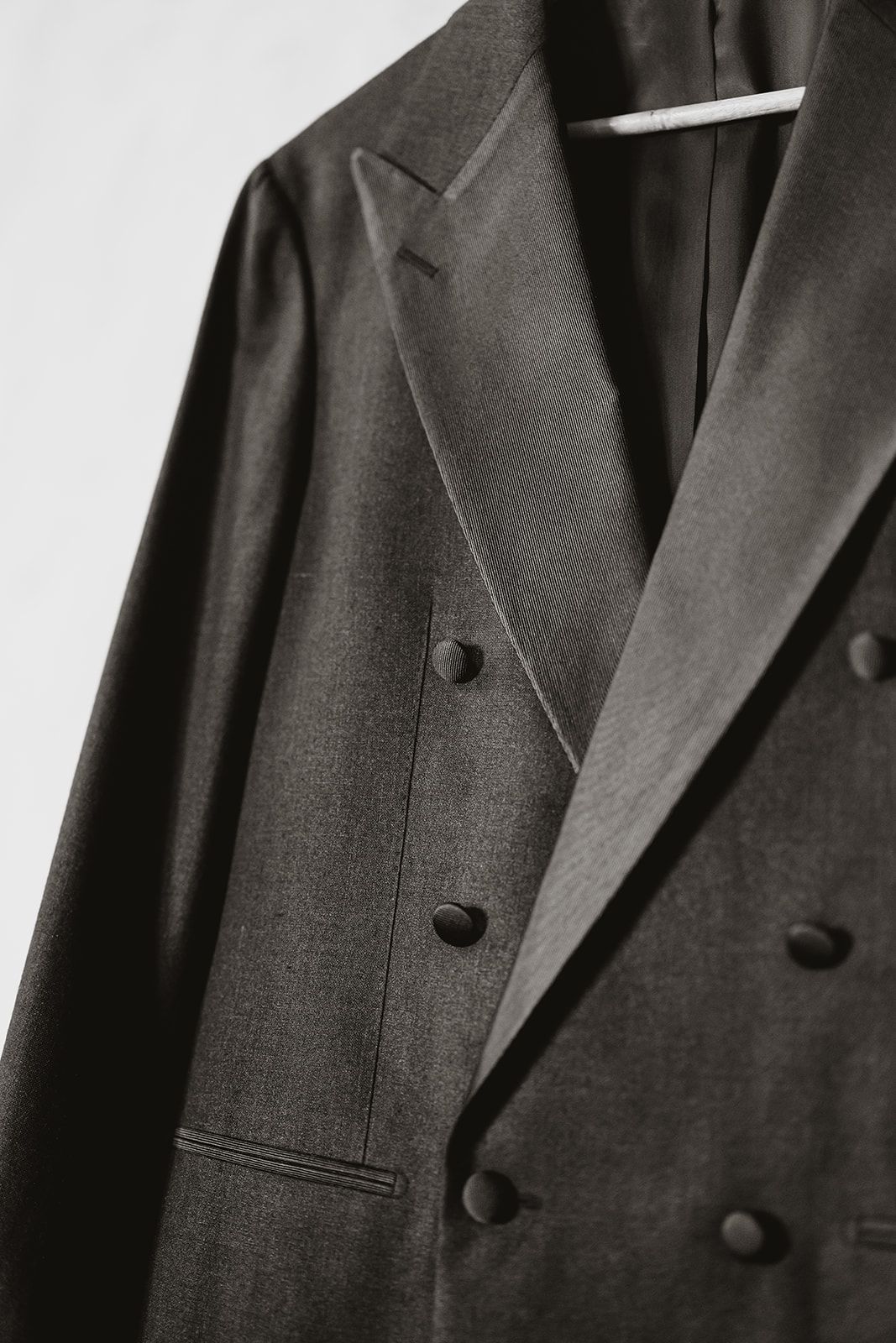 Close-up details of a dark formal suit jacket with buttons and lapels.