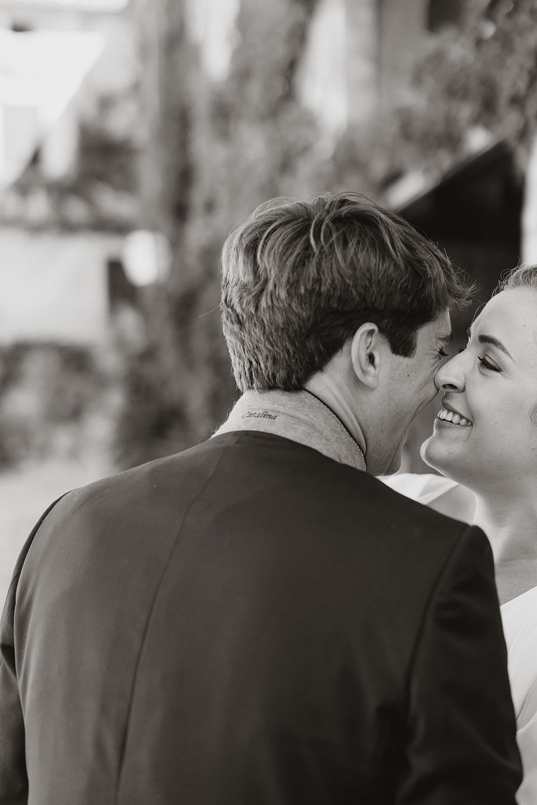 Black and white candid wedding photo capturing intimate moment between newlyweds.
