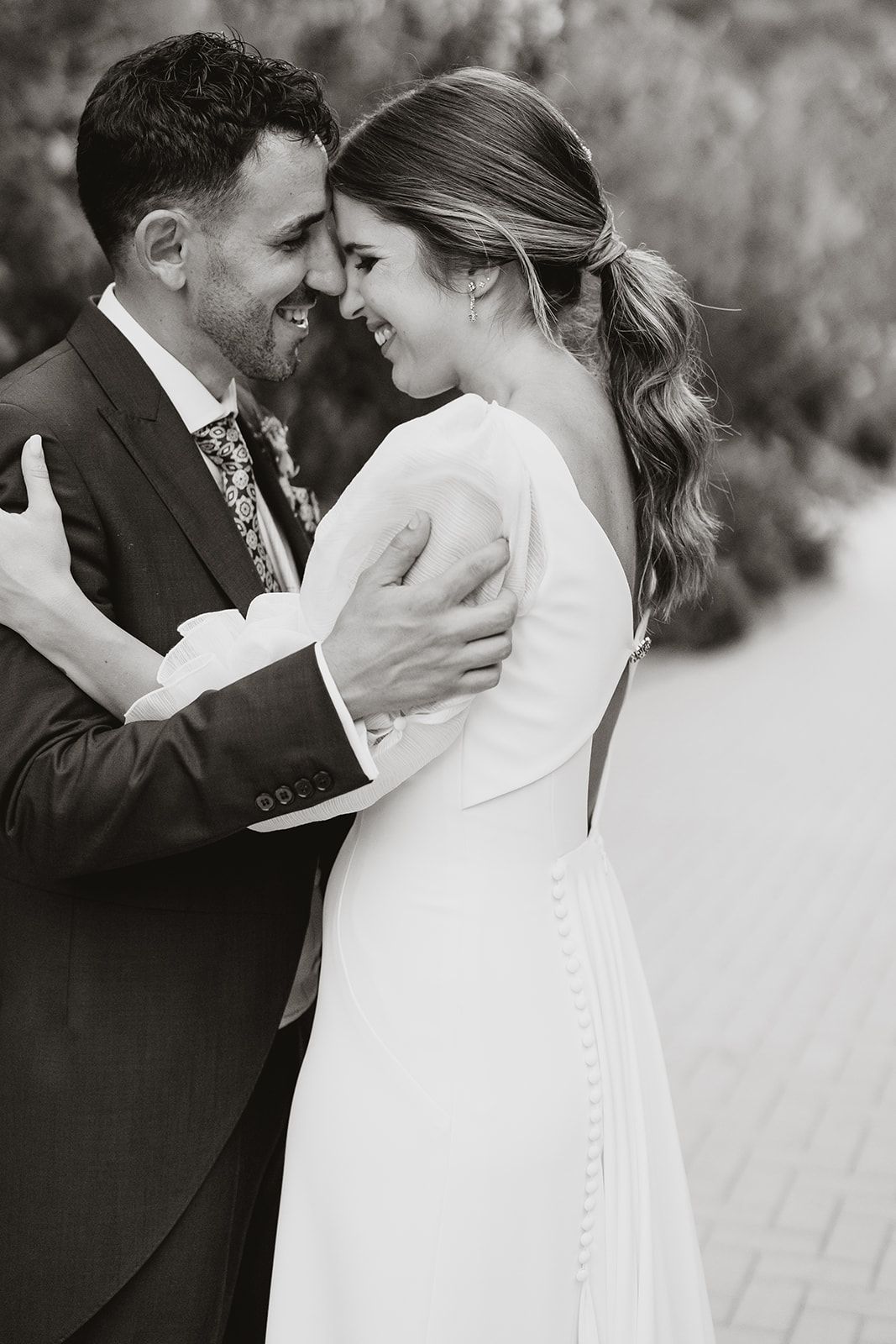 Black and white intimate portrait of newlyweds sharing a tender moment outdoors.