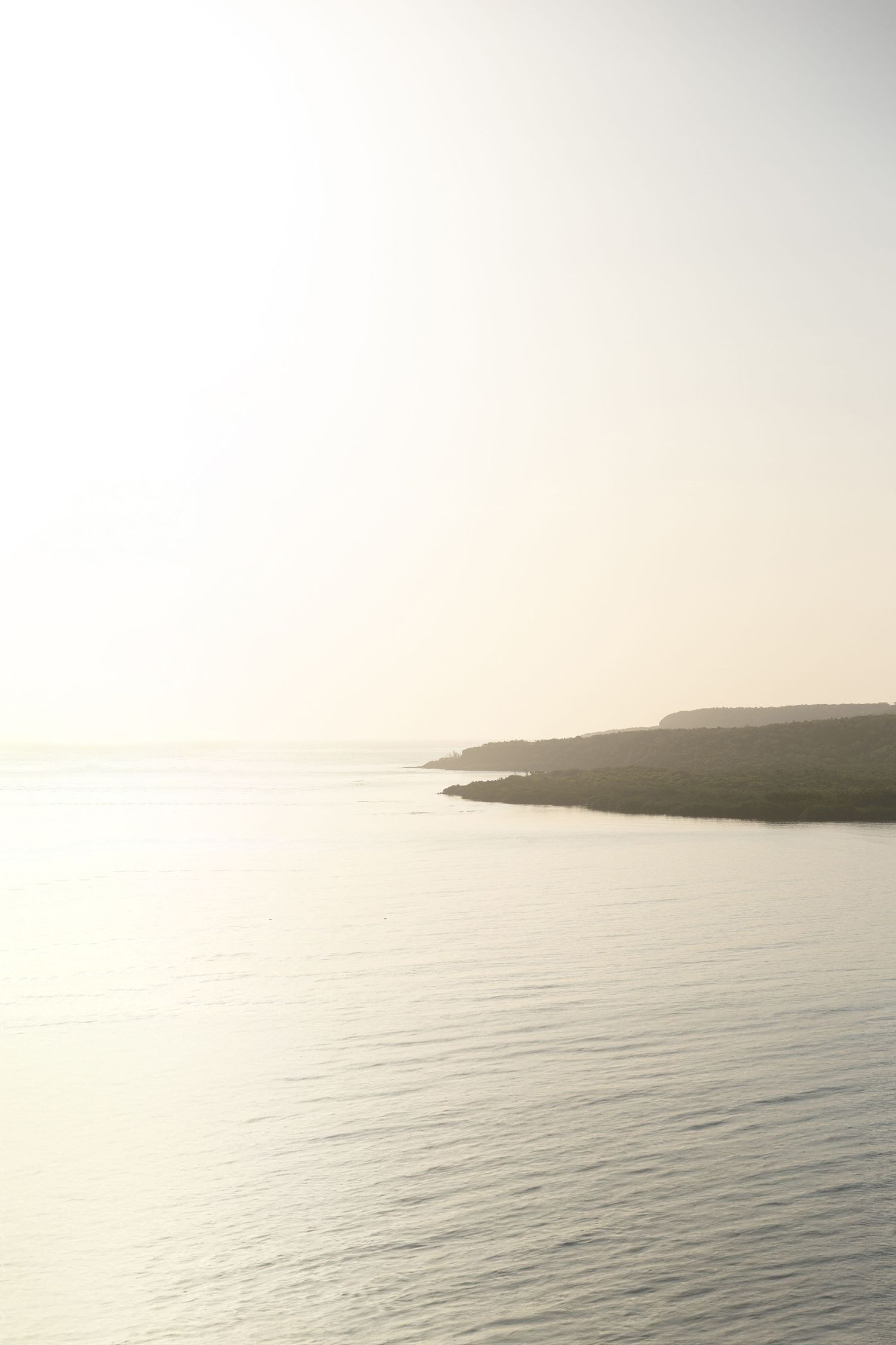 Misty coastal seascape with distant cliffs in soft natural light.