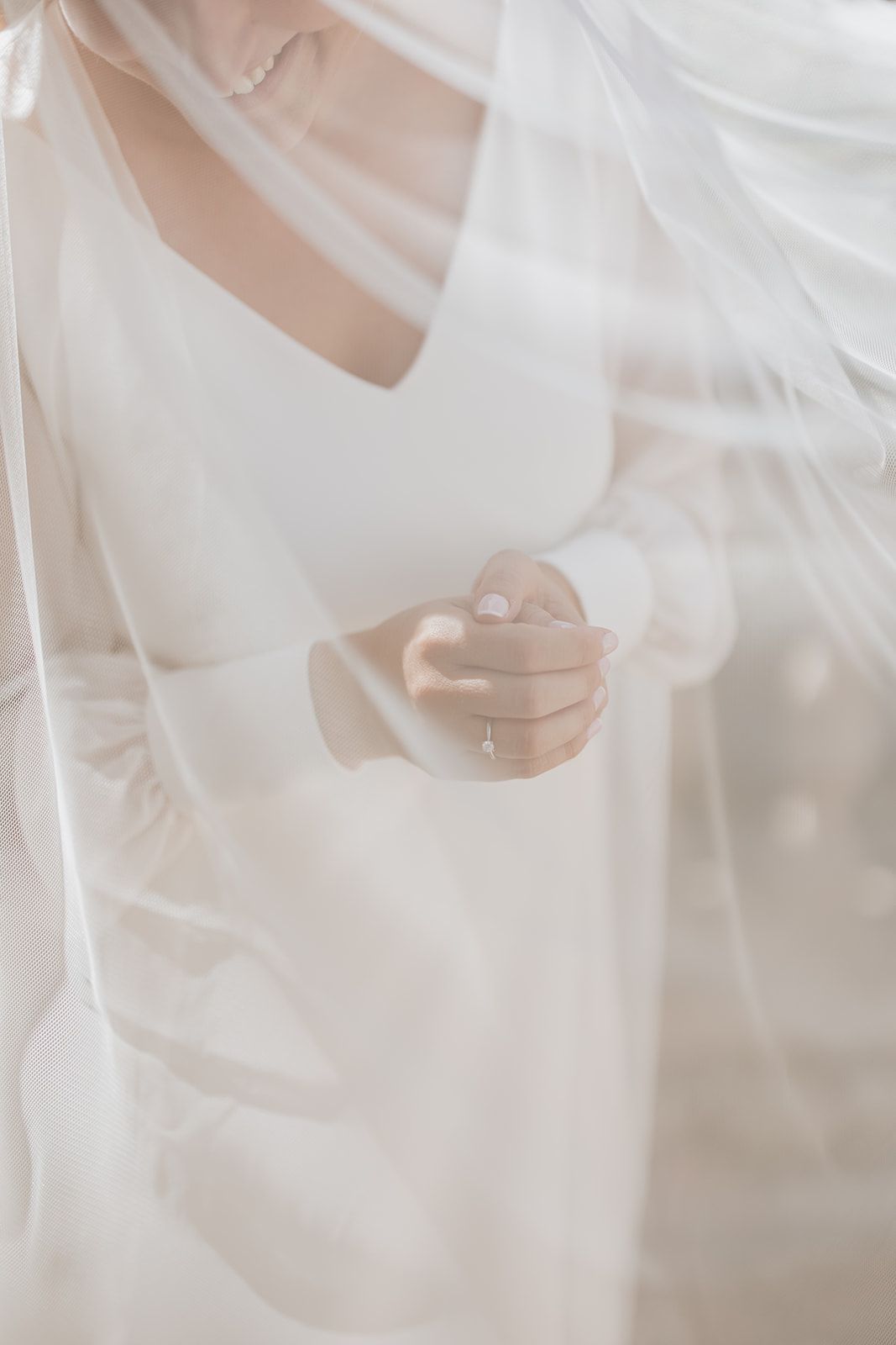 Detail shot of wedding dress with delicate veil overlay in soft natural light.