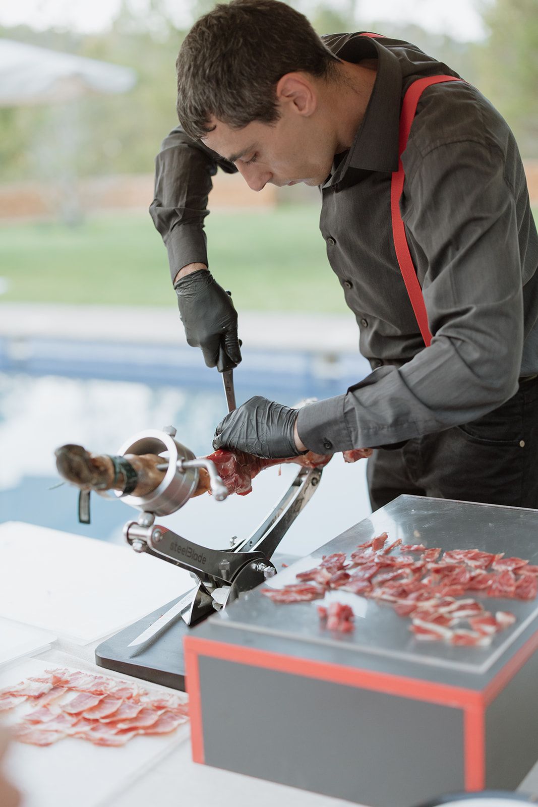 Chef preparing food on black serving trays at catering station.
