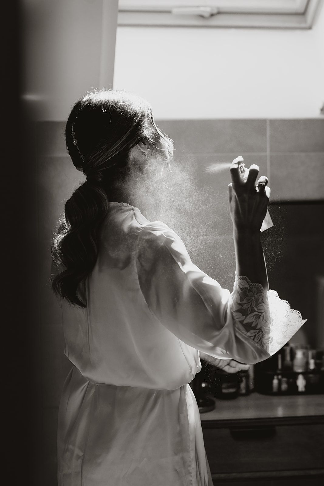 Artistic black and white photo of someone in a robe with hair styling products.