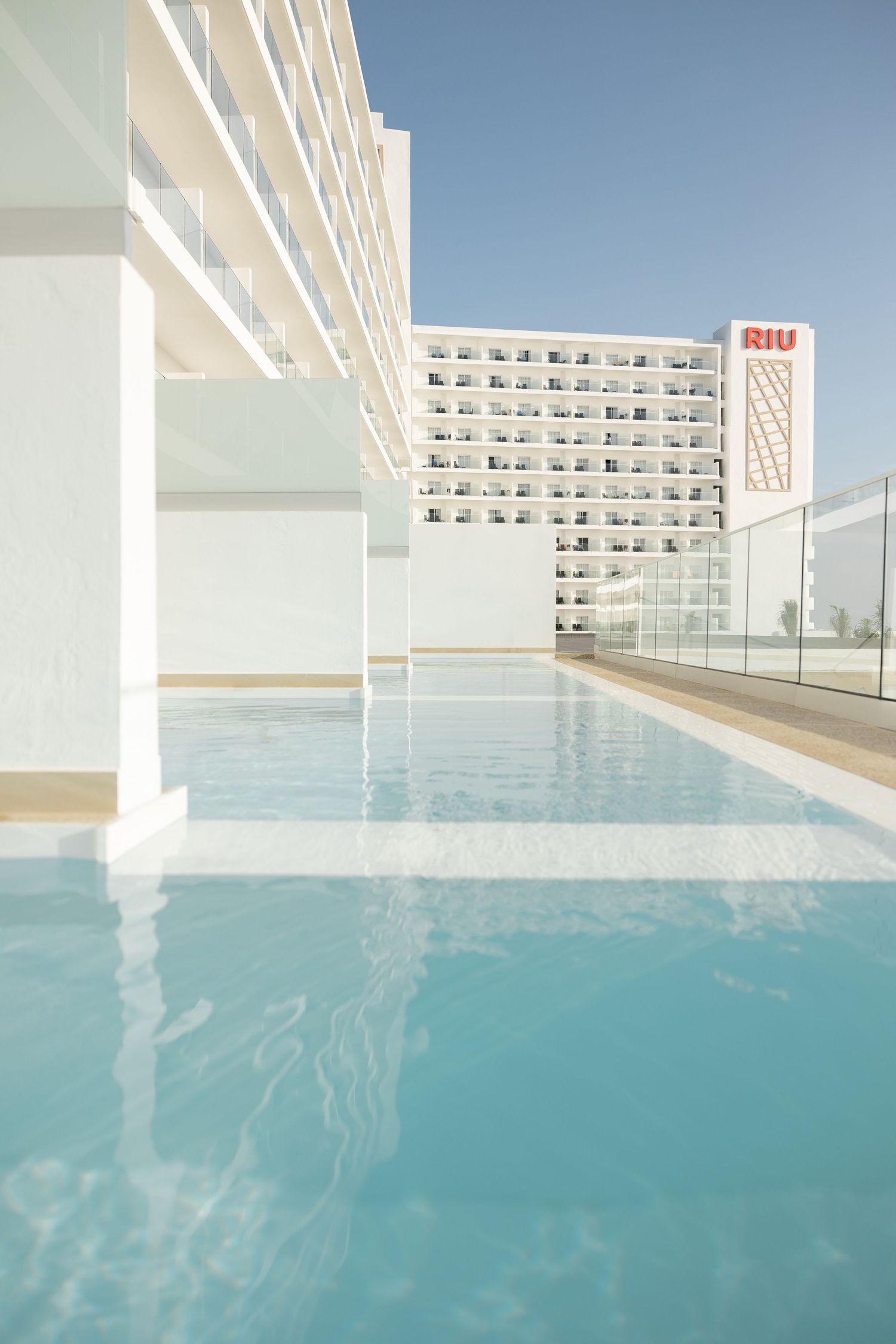 Modern infinity pool with turquoise waters framed by contemporary white hotel architecture.