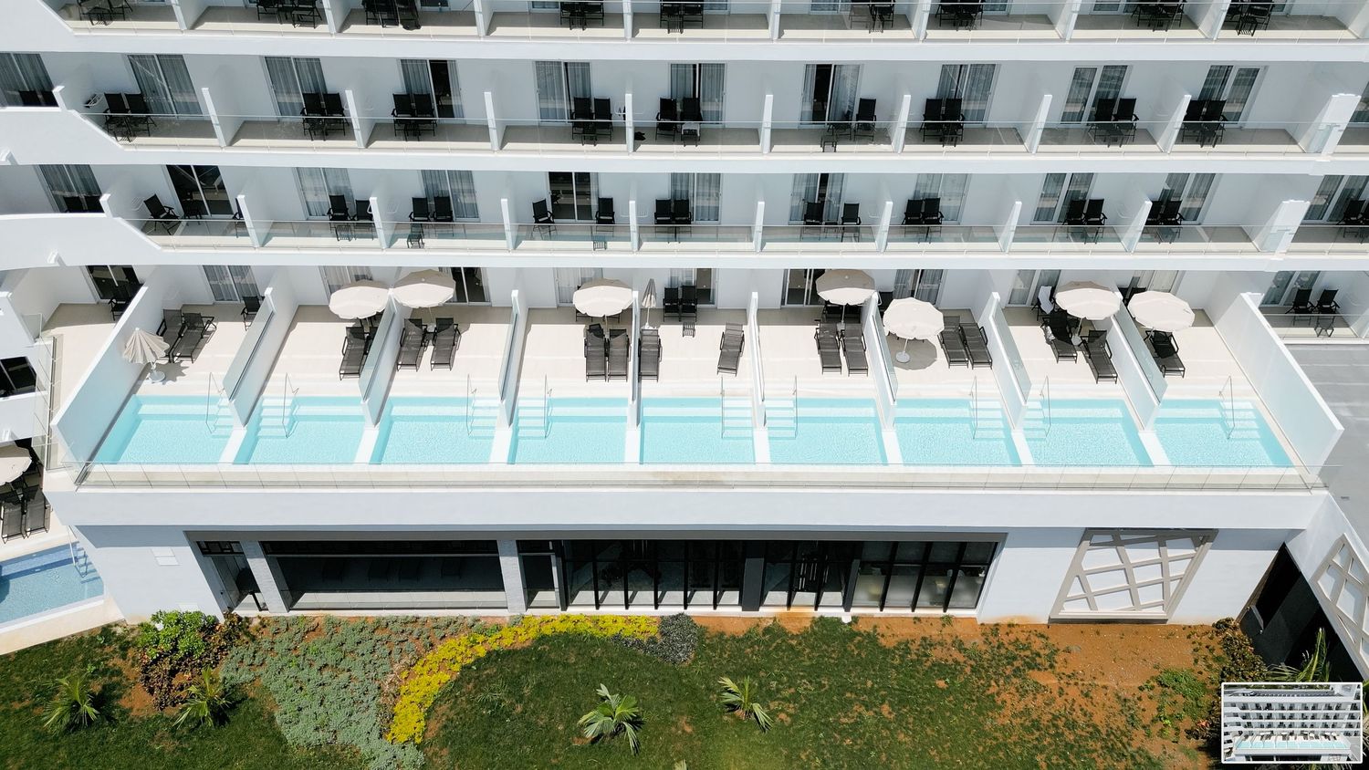 Aerial perspective of hotel swim-up suites featuring private pools and furnished balconies.