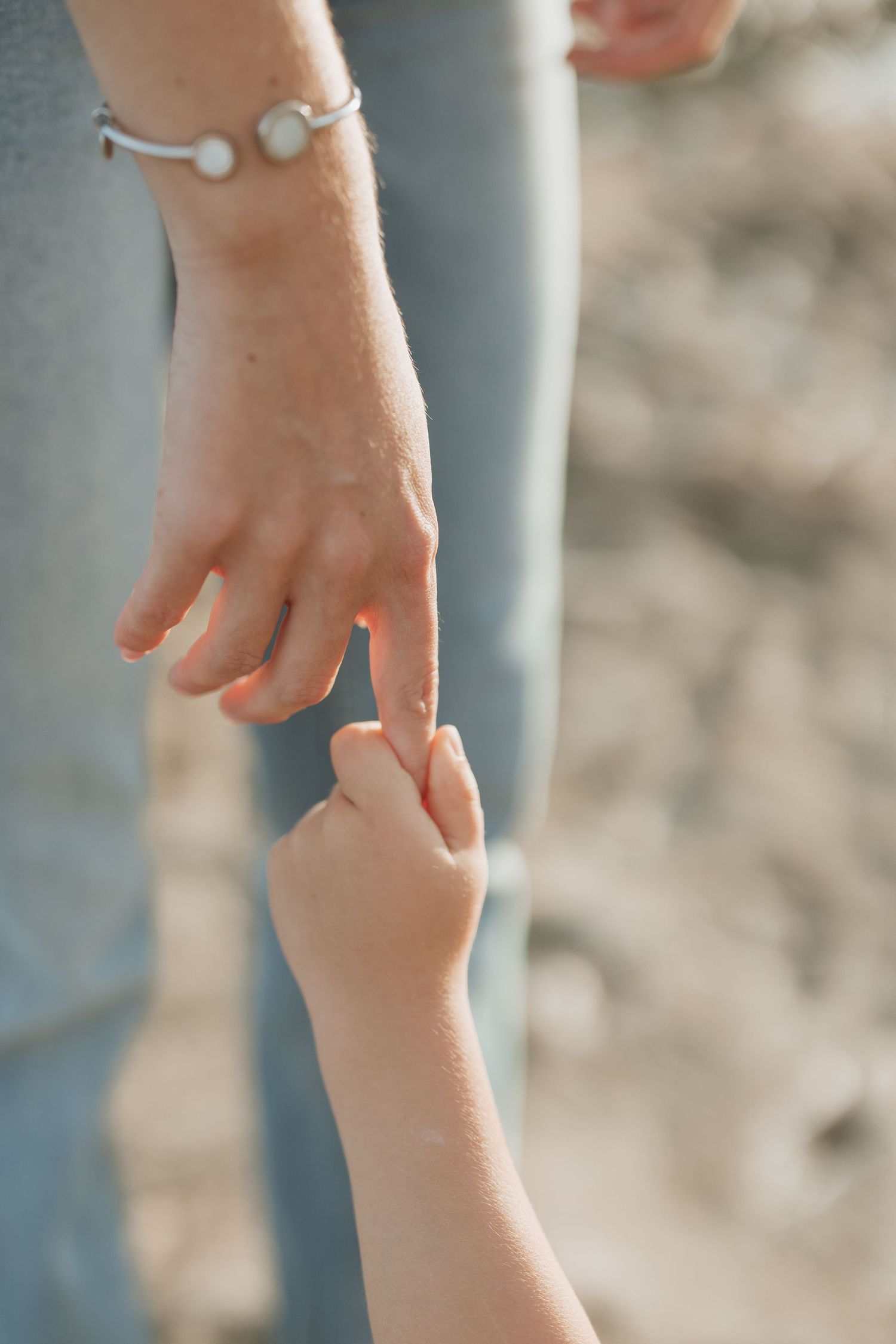 Close-up of adult and child's hands touching with bracelet detail.