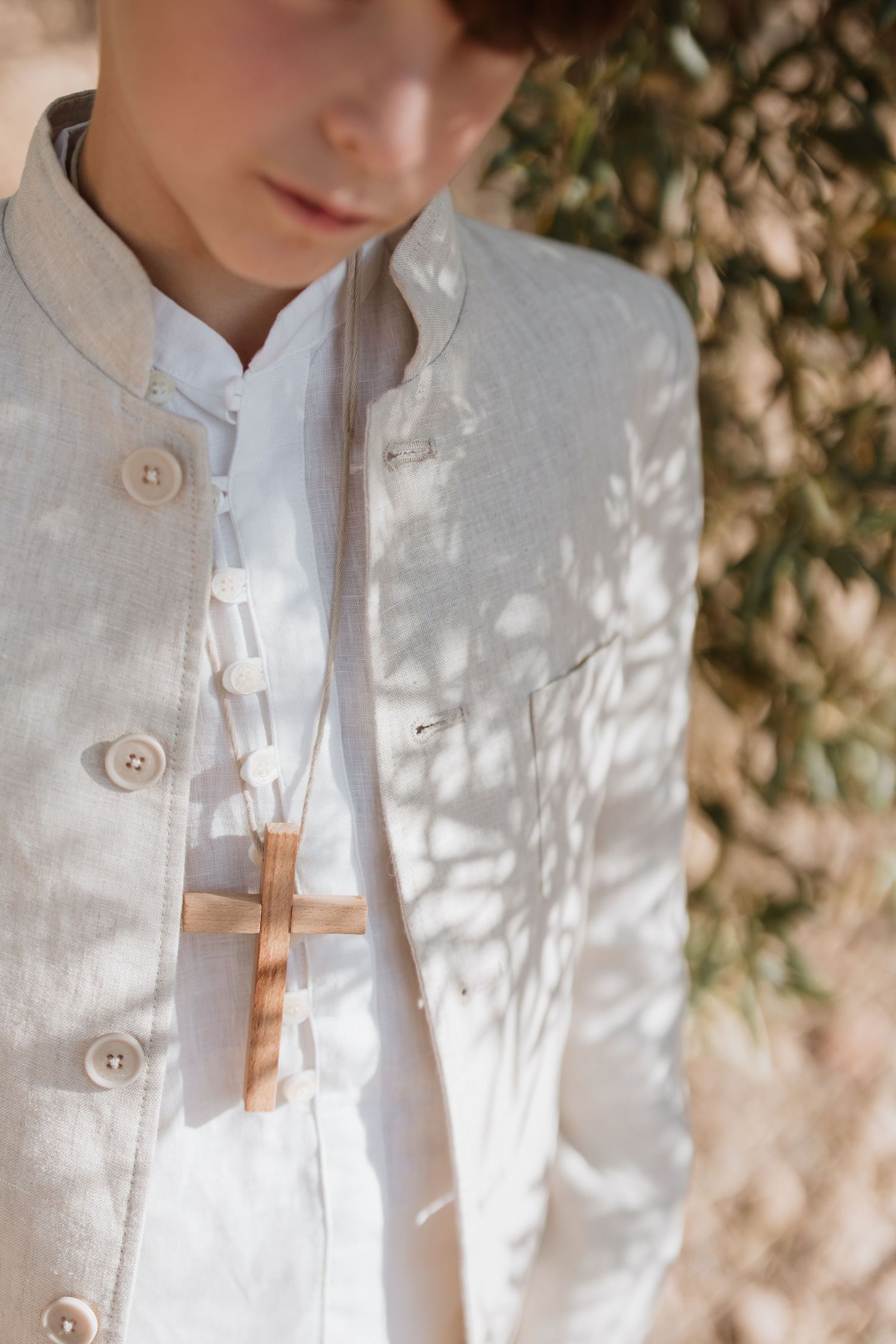 Details of a white linen shirt with wooden clothespins in natural dappled sunlight against a textured wall background.