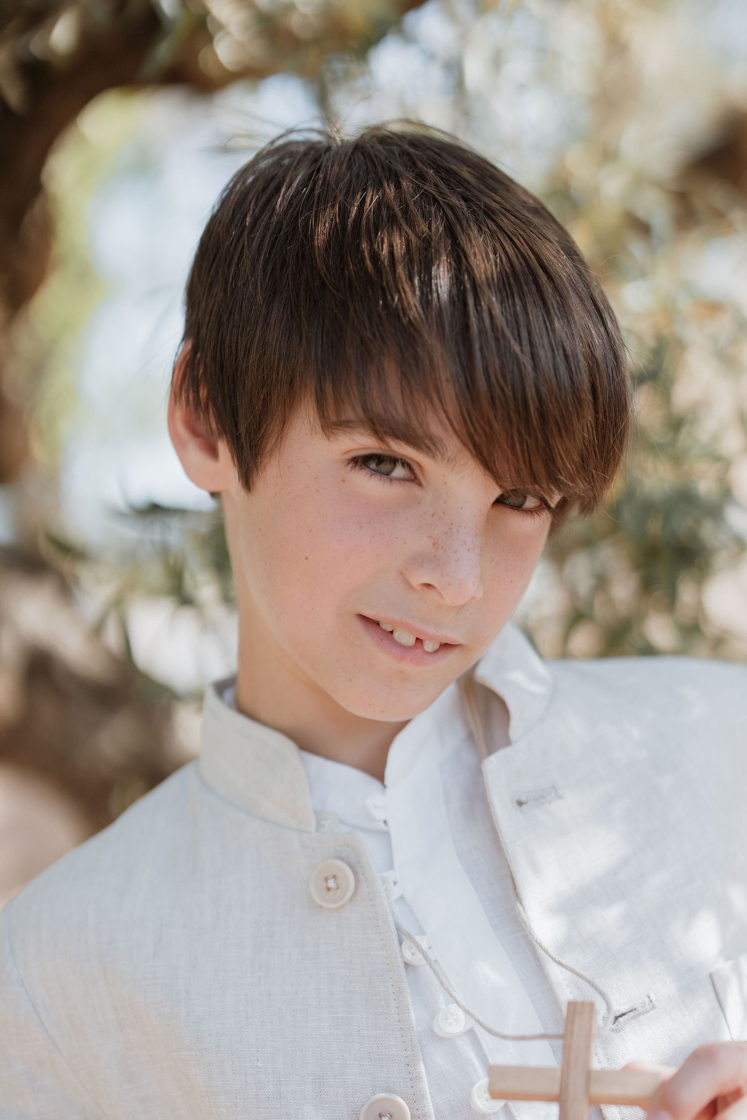 A series of portraits showing a child in a white button-down shirt smiling against a soft-focus outdoor background.