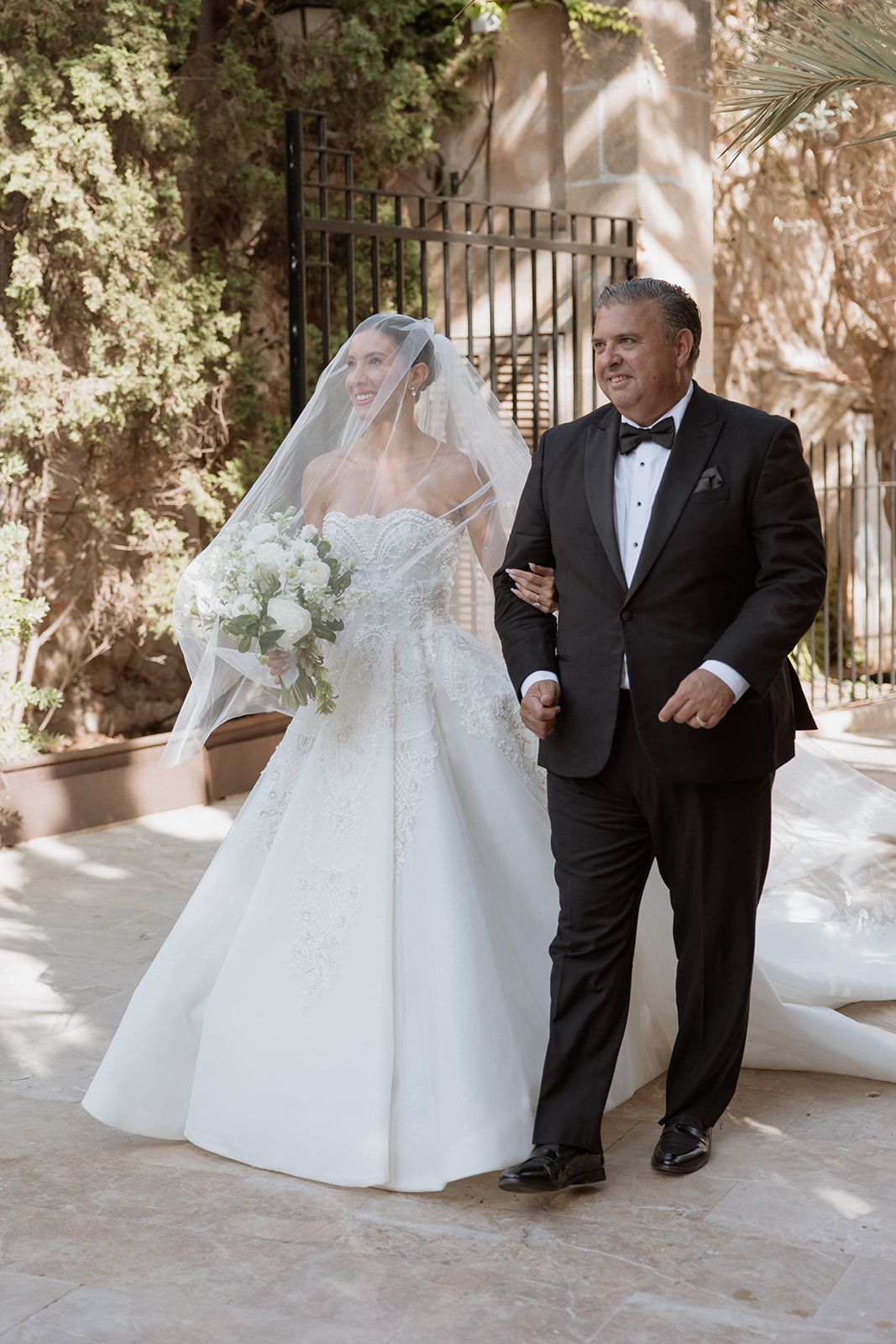 A wedding scene in a sunlit courtyard features the couple in formal attire with a beautiful white dress and classic tuxedo.