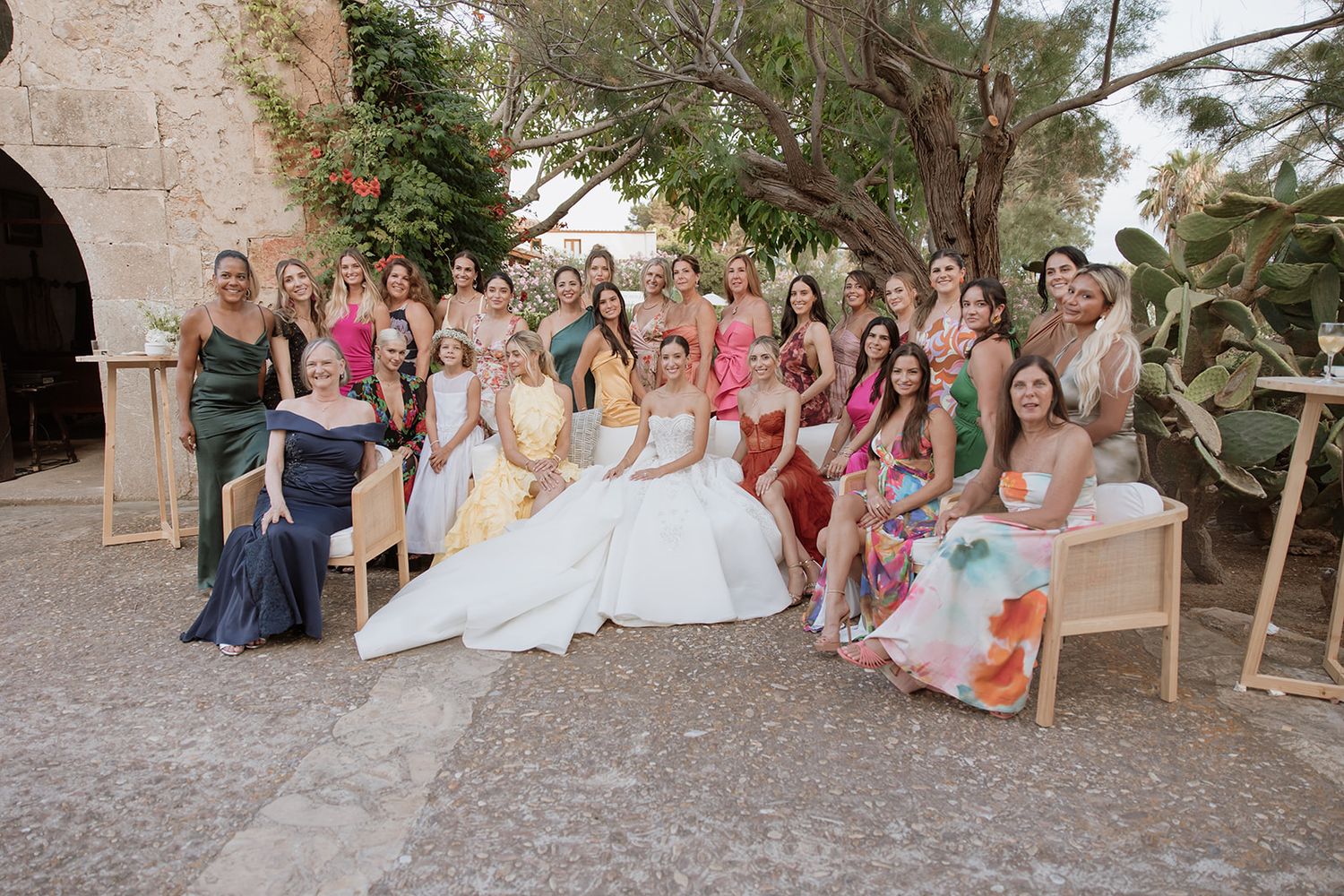 Wedding party gathered for a group photo at an elegant stone venue.